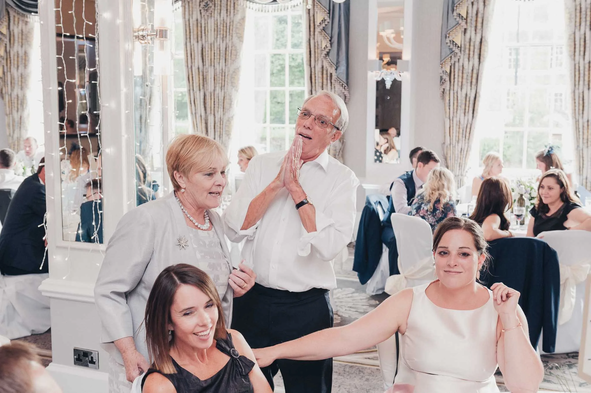 Family members sharing a lighthearted moment together during the wedding breakfast.