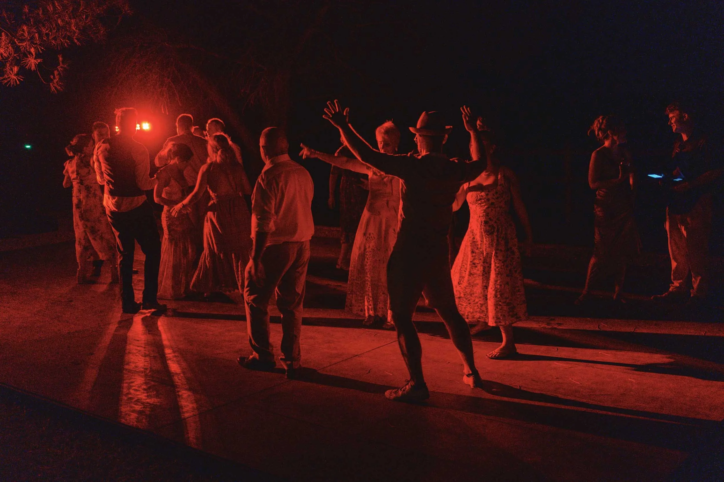 Wedding guests dancing under red lighting at night at Paradis des Vignes, Charente
