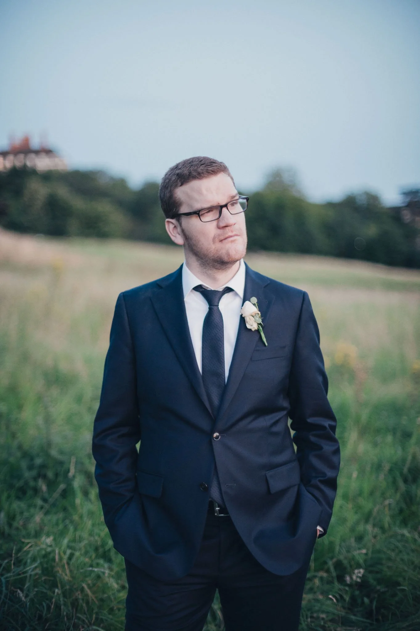 Portrait of the groom standing outdoors in his navy suit.