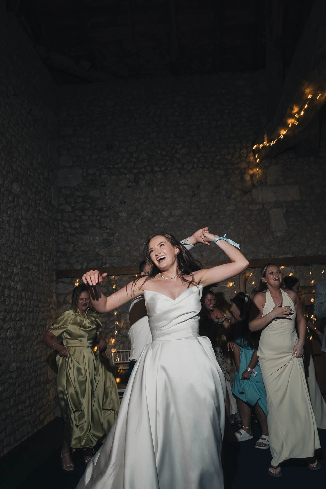 Bride dancing with guests inside the barn at Manoir de Longeveau.