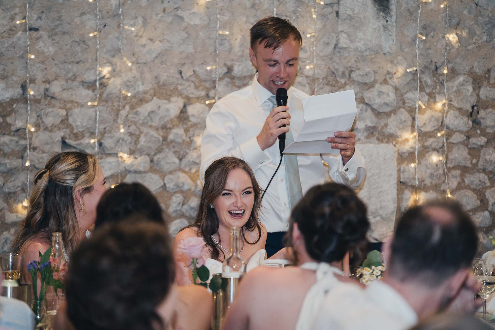 Bride laughing during a speech while seated at the top table.