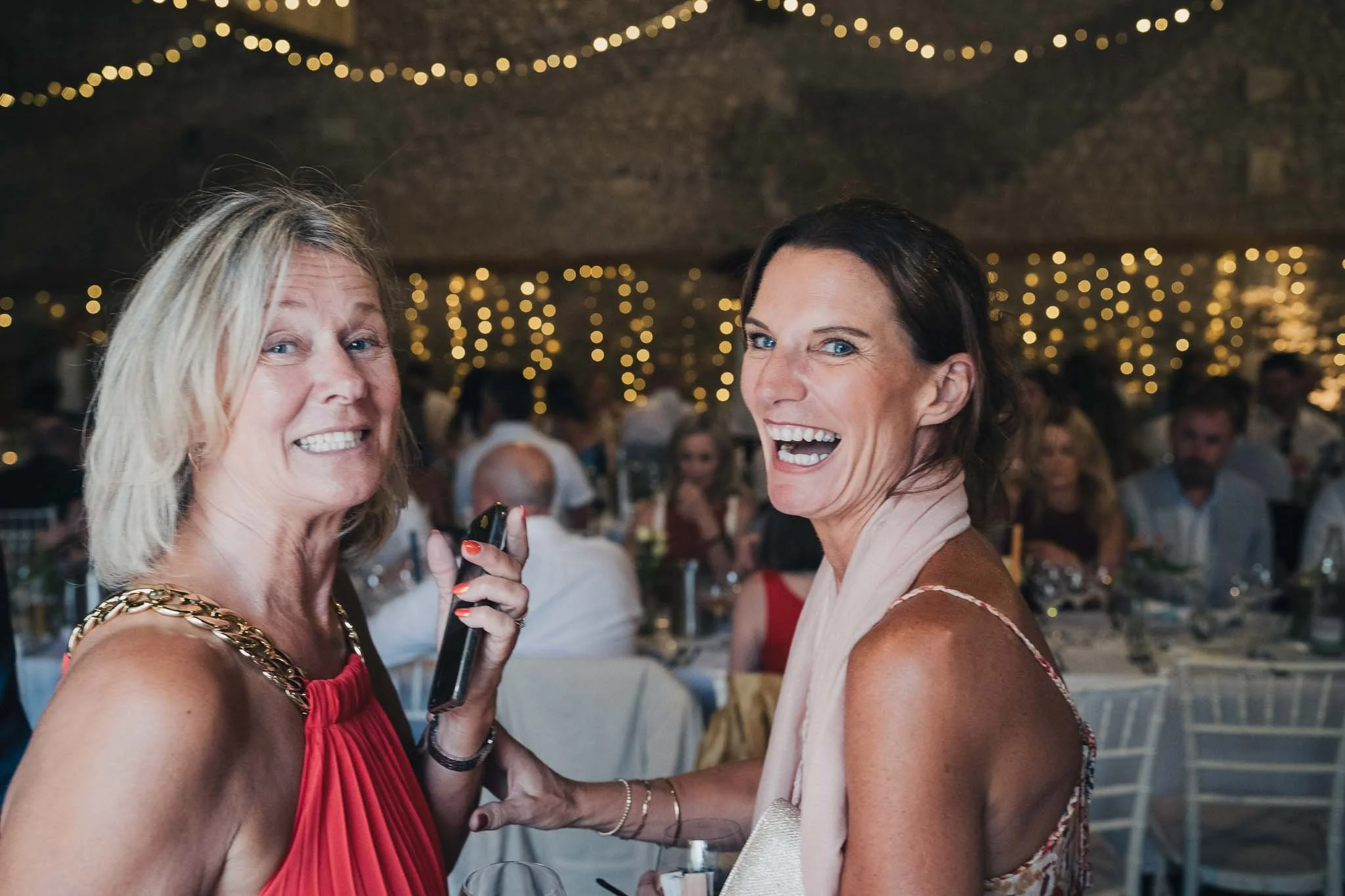 Two guests laughing and holding the microphone during speeches at the reception.