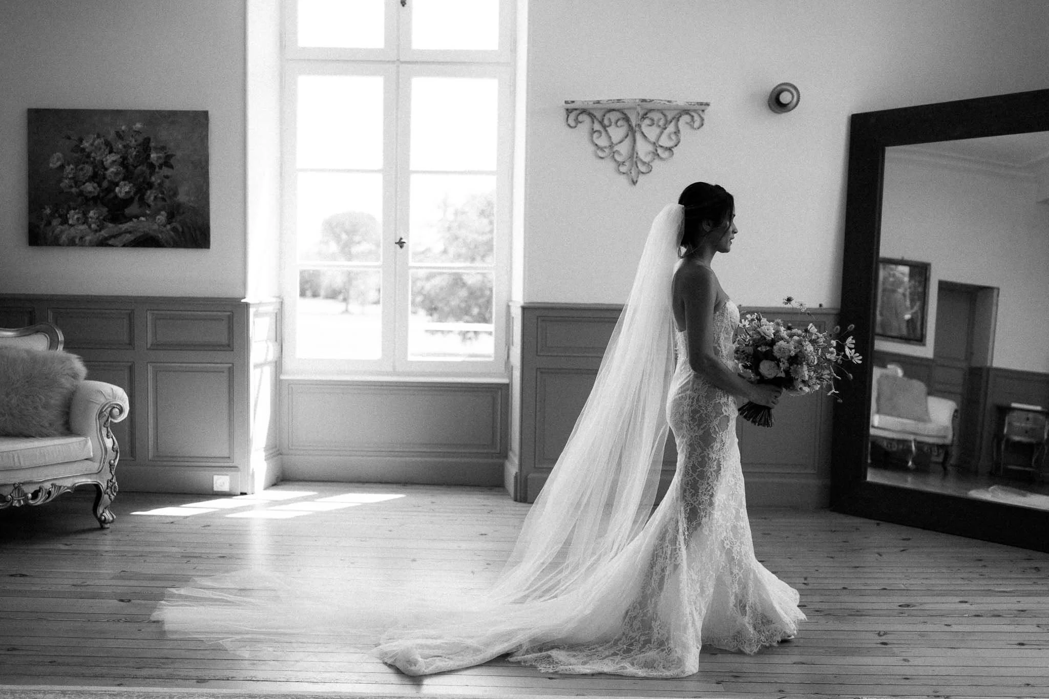 Black and white full length photograph of the bride in an empty room at Château de Sainte Croix, Dordogne