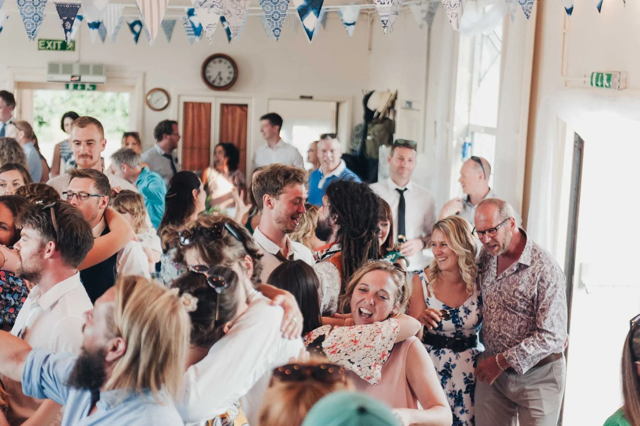 Couple dancing closely in the middle of a busy dance floor during the reception.
