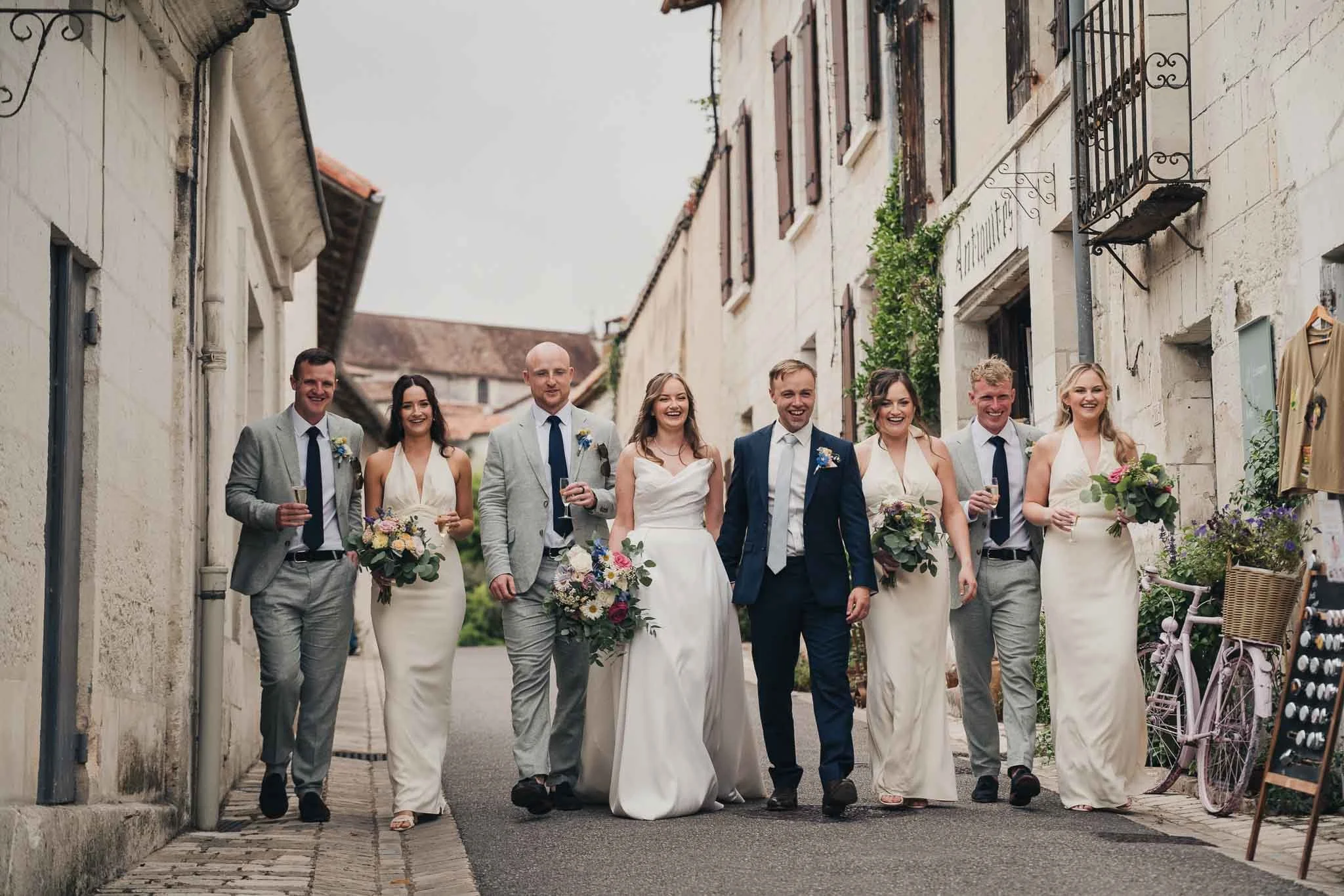 Bridal party walking together through the village streets of Aubeterre-sur-Dronne after the ceremony.