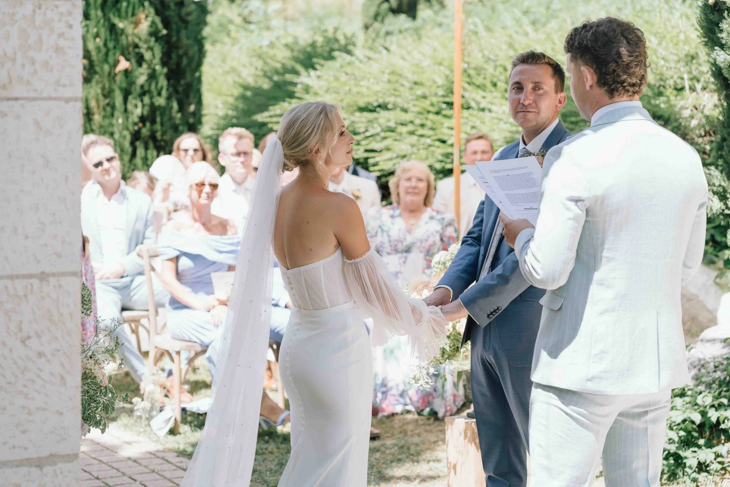 Couple holding hands during their vows in front of guests at a Château du Raysse ceremony