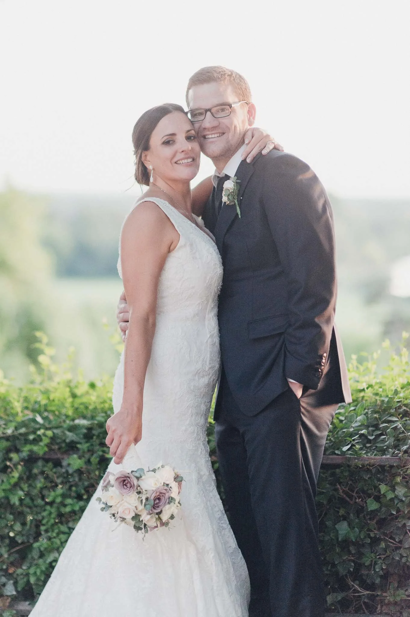 The couple standing together at sunset, smiling during their portrait session.