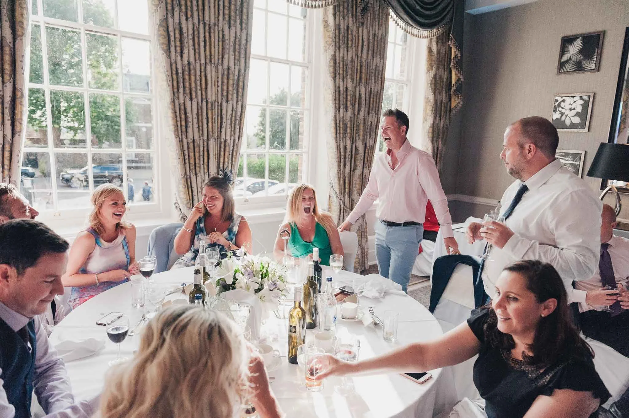 Guests talking and enjoying drinks around their table during the wedding breakfast.