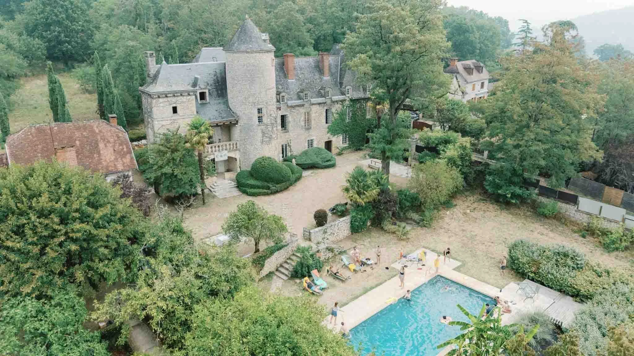 Aerial view of Château du Raysse wedding venue in the Dordogne with pool and grounds on a hazy summer day