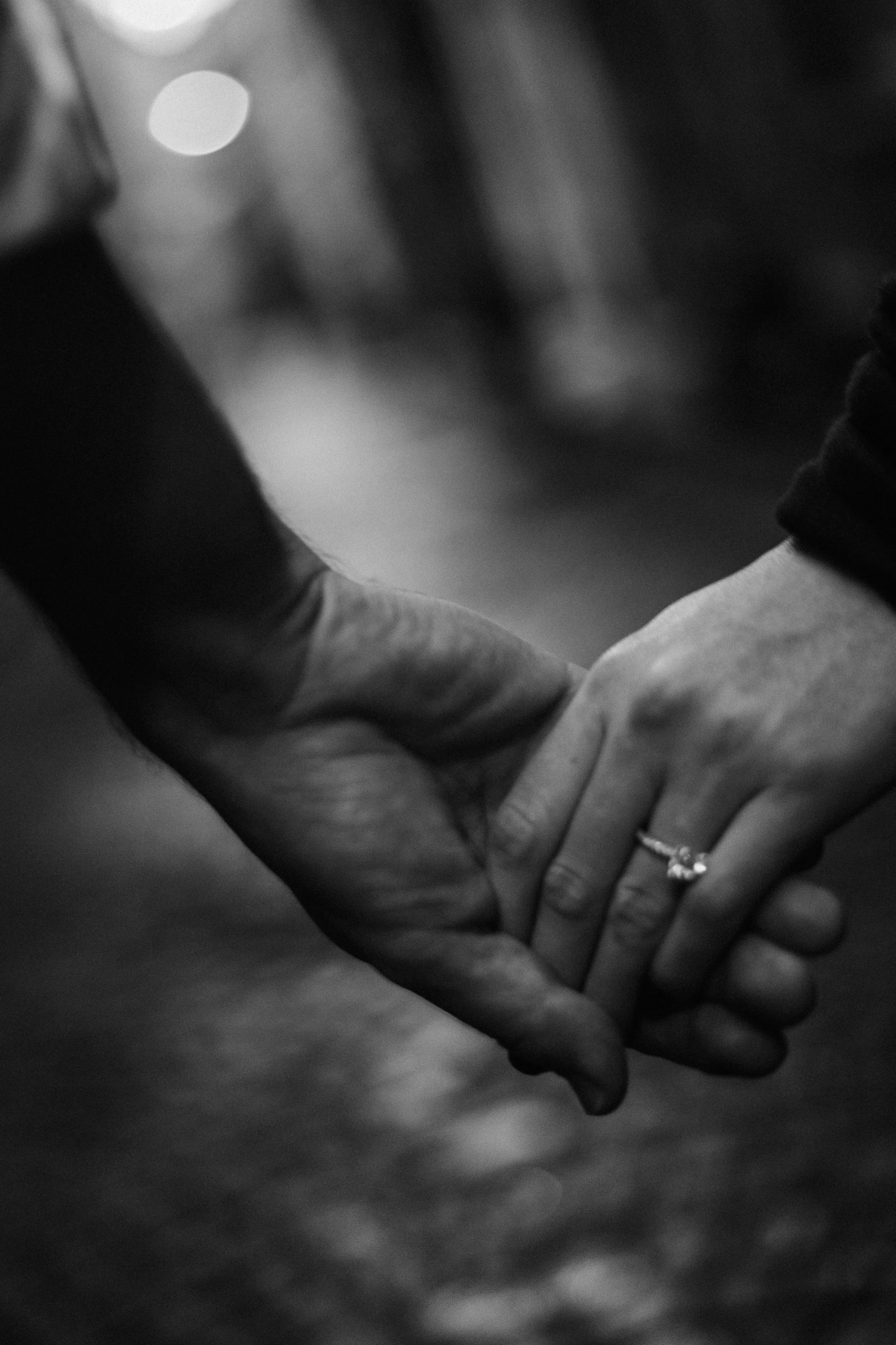 Close-up of engaged couple holding hands with engagement ring visible during a Bordeaux engagement session.
