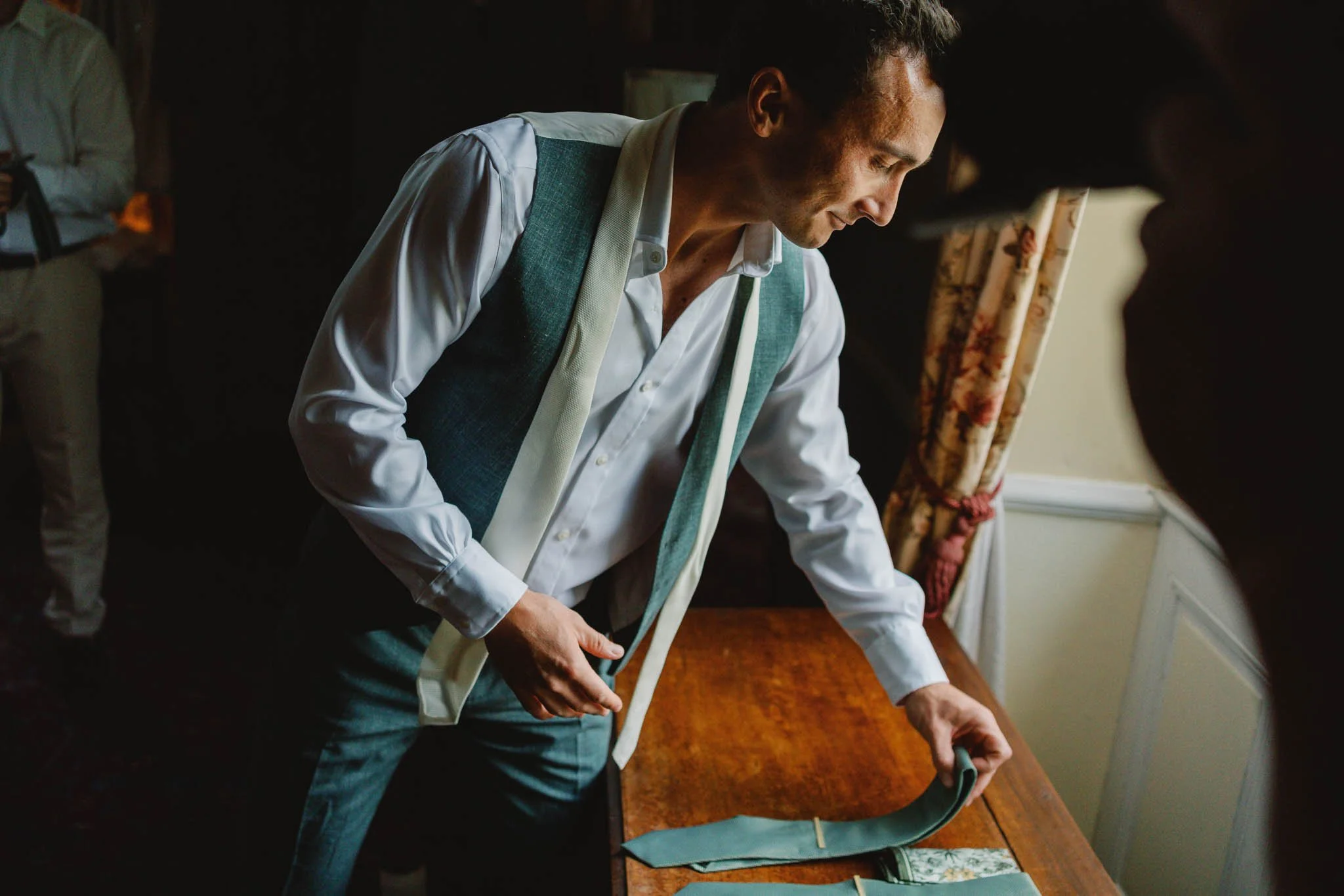 Candid photograph of the groom selecting his tie at Château Lagorce, Bordeaux