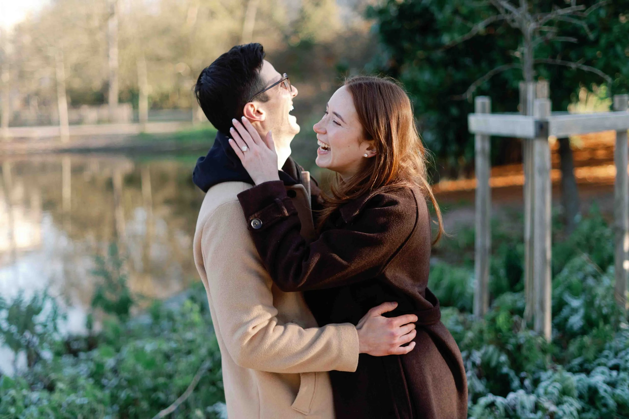Newly engaged couple laughing by the lake in Jardin Public, Bordeaux, on a frosty winter morning
