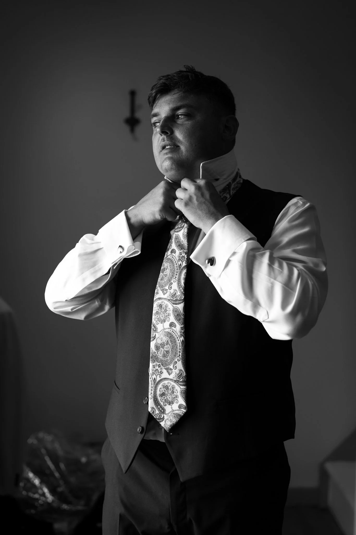 Black and white photograph of the groom adjusting his tie during a speech at Paradis des Vignes, Charente