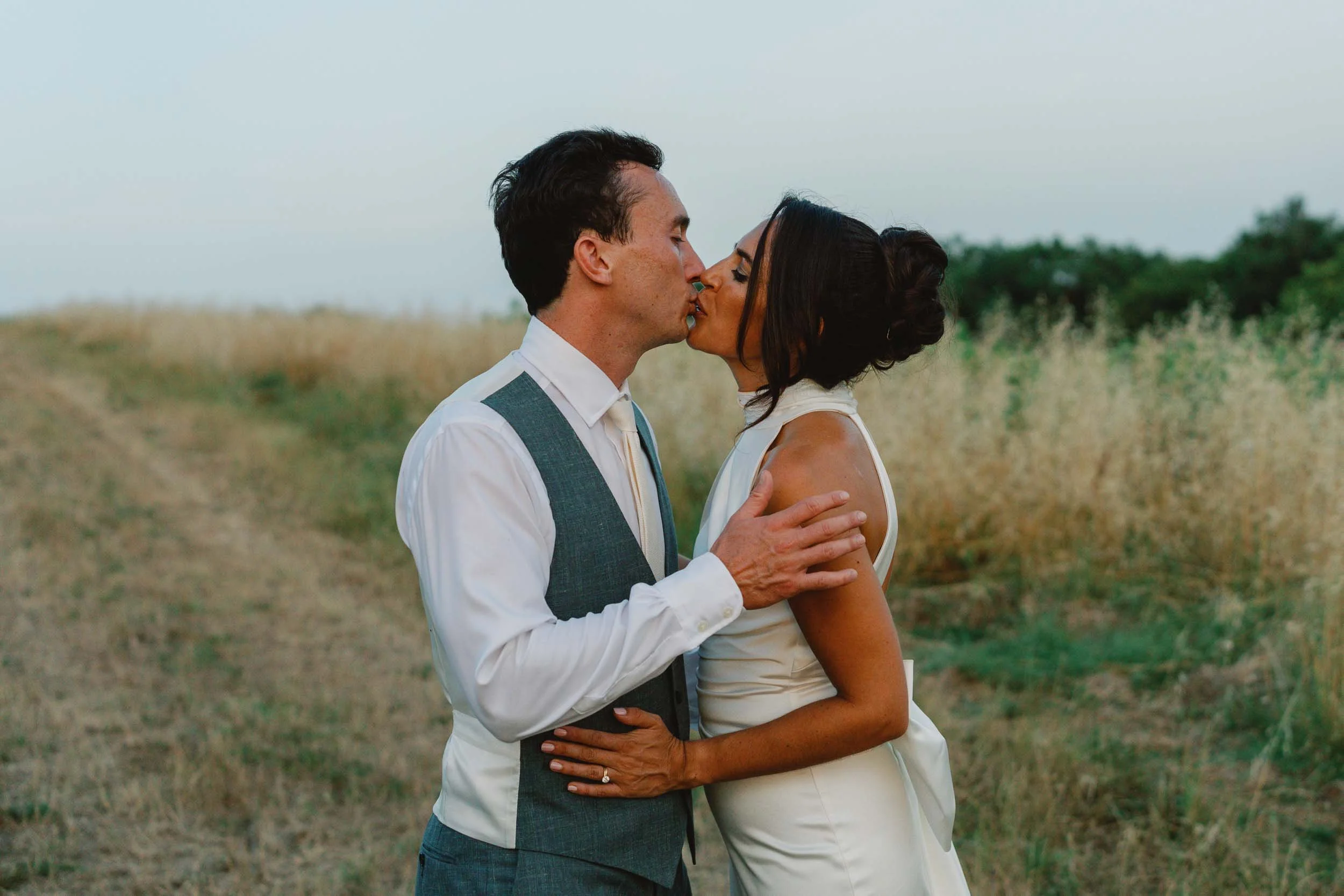 Bride and groom kissing in a golden field near Château Lagorce, Bordeaux