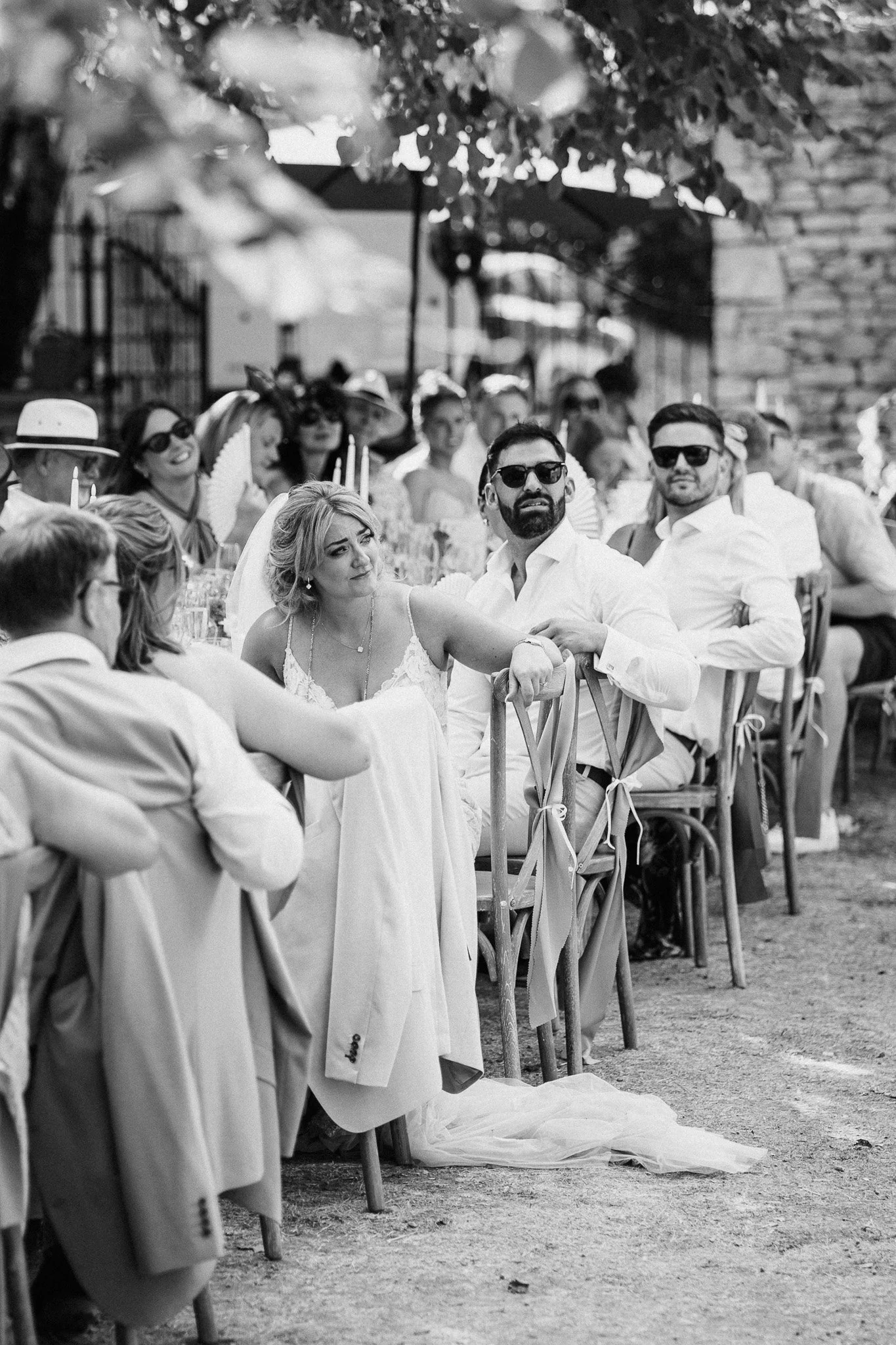 Guests seated at long tables during the outdoor wedding reception, captured in black and white.
