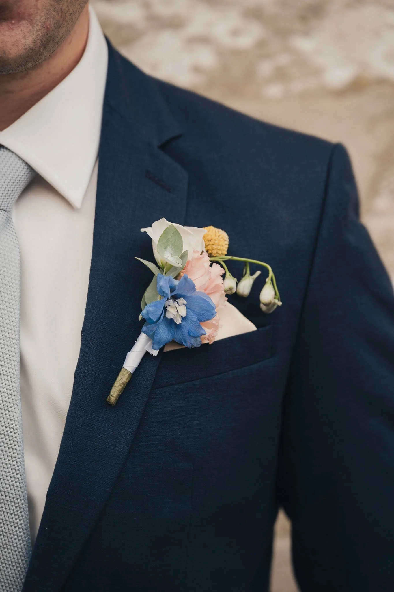 Close-up of the groom’s buttonhole featuring blue and white flowers.