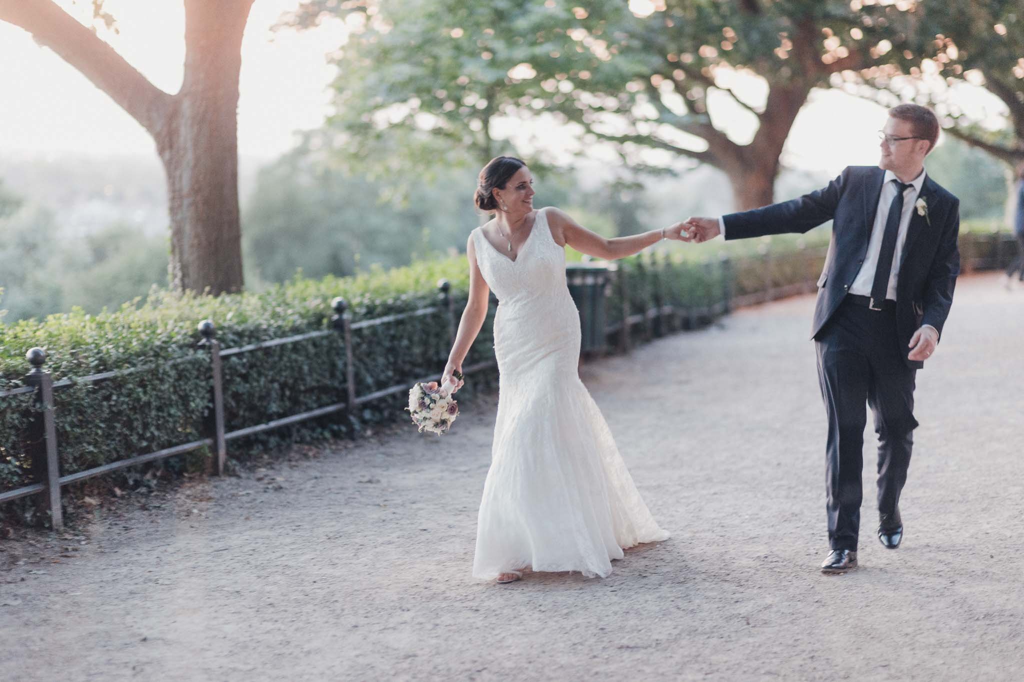 The bride spinning playfully as the groom holds her hand on a shaded path.