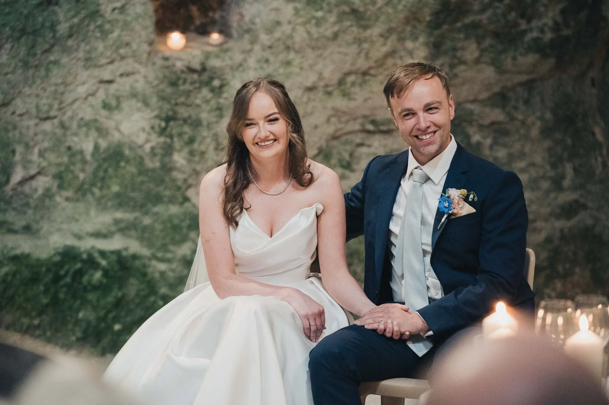 Bride and groom seated together, smiling, during the ceremony at the Église Souterraine Saint-Jean.