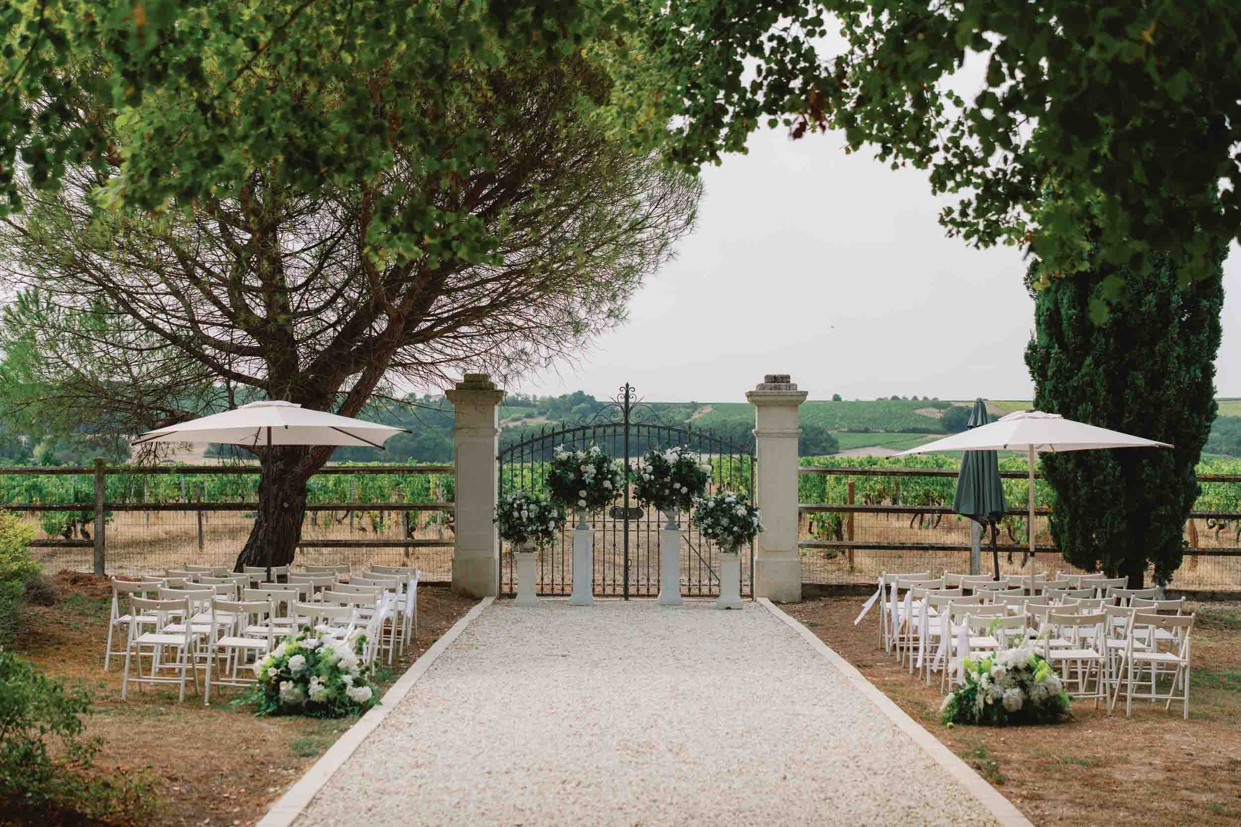 Empty ceremony aisle framed by trees leading to a vineyard gate at Paradis des Vignes, Charente