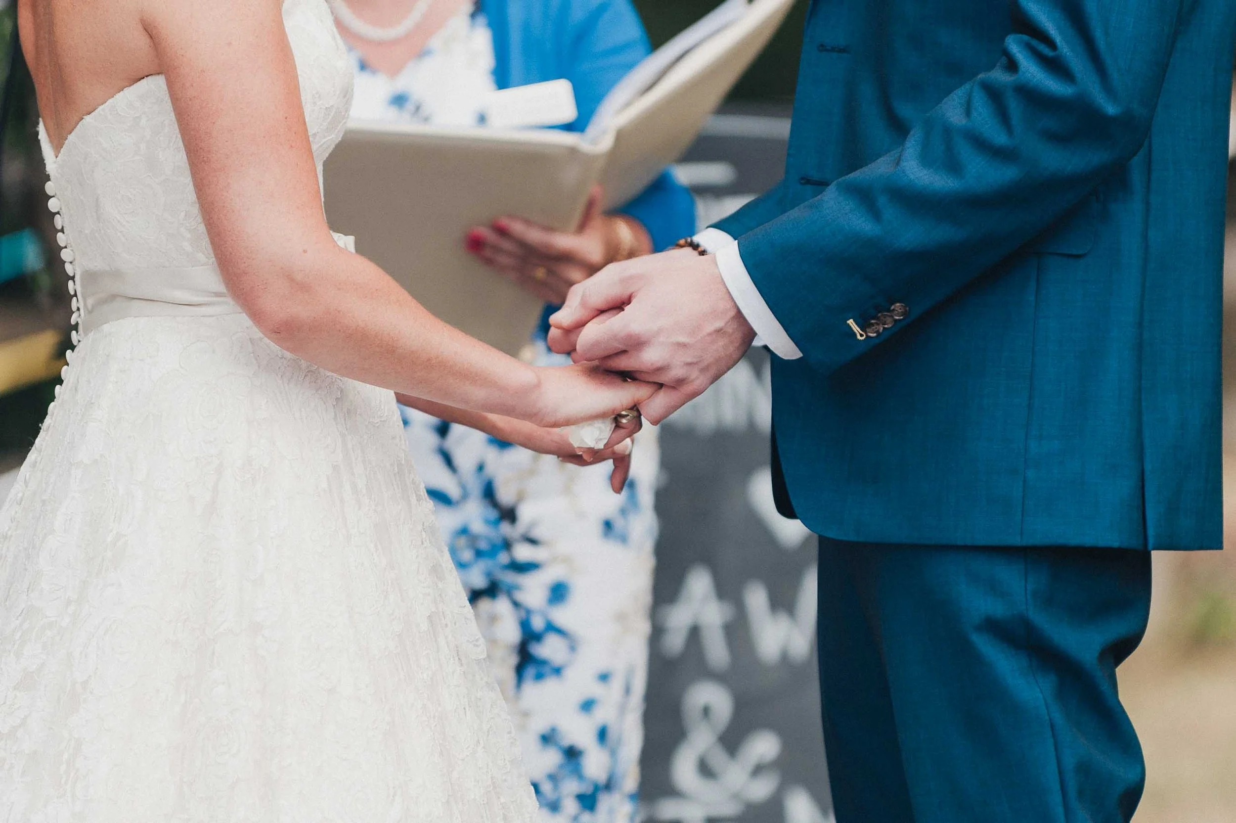 Close view of the couple holding hands during the ring exchange, captured calmly during the wedding ceremony.