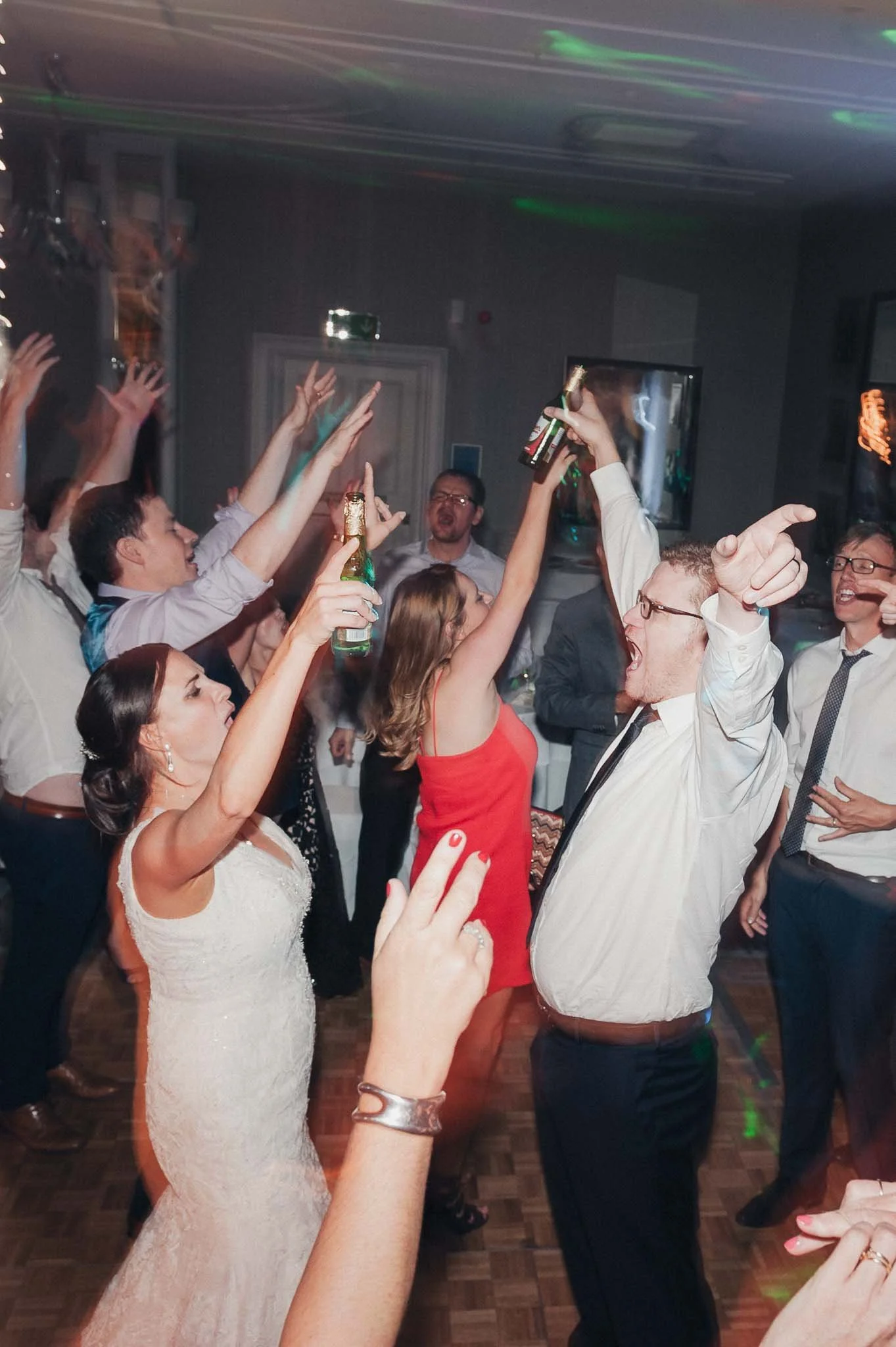 Guests raising their arms and celebrating on a busy wedding dance floor.
