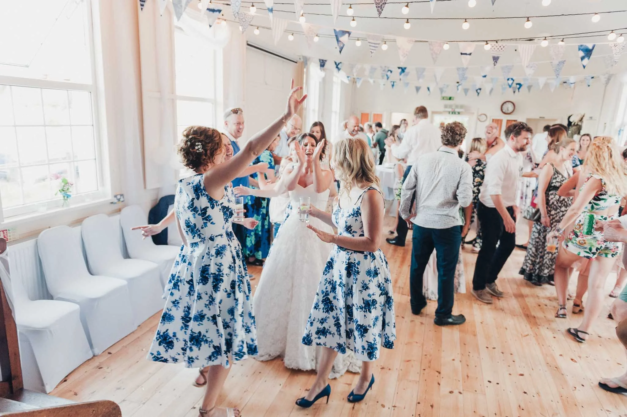 Guests dancing and celebrating on the wooden floor of the village hall during the evening reception.