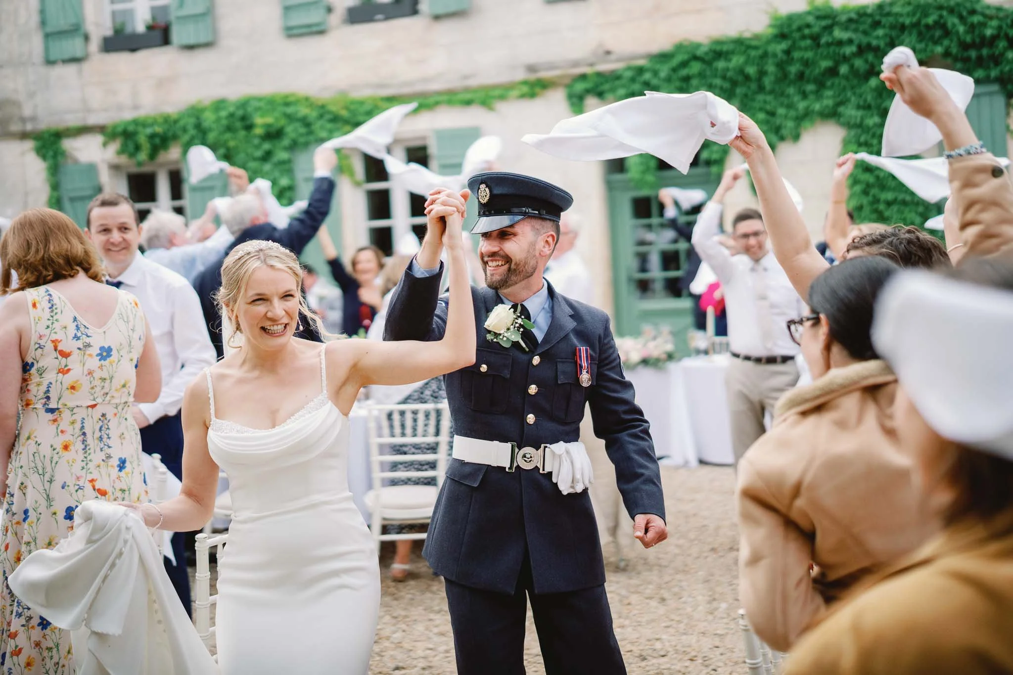 Guests waving napkins as the military couple enter the wedding breakfast at Manoir de Longeveau, Charente