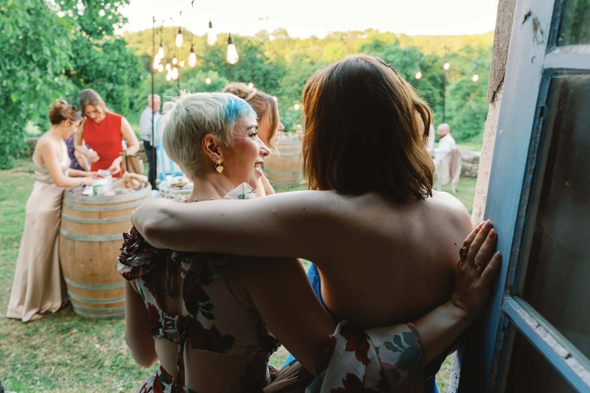 Two wedding guests sharing a candid moment by a window at Château de Panisseau, Dordogne