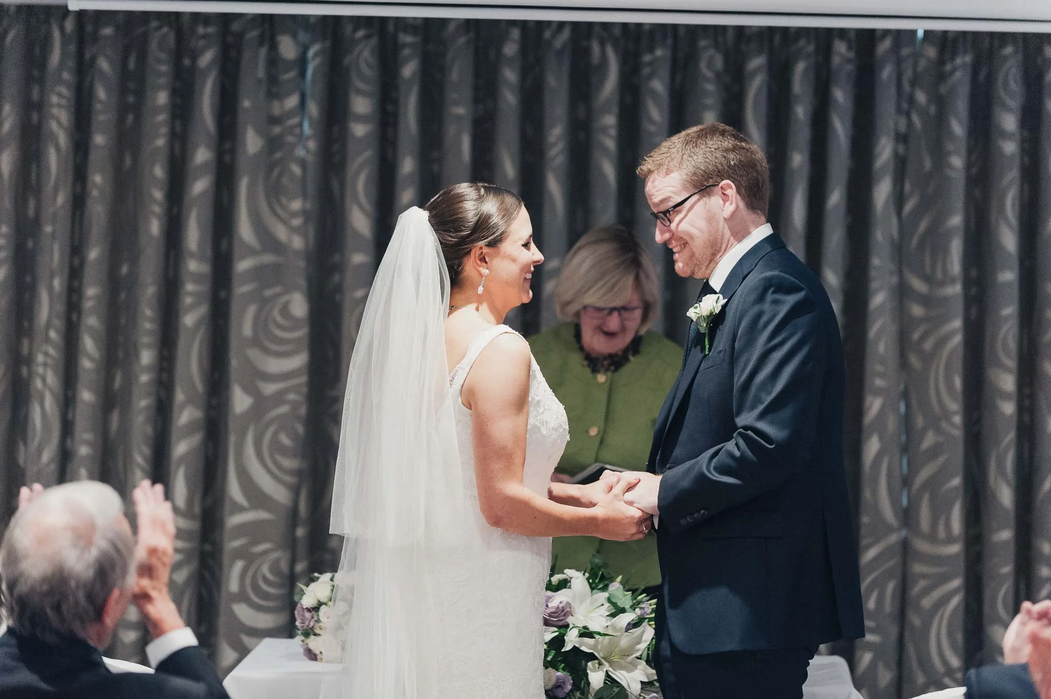 Bride and groom holding hands during their indoor ceremony at the Richmond Hill Hotel.