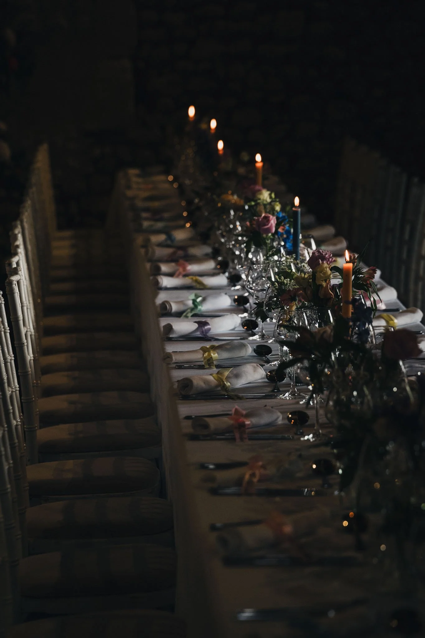 Long dinner table set for the wedding meal at Manoir de Longeveau, decorated with candles and flowers.
