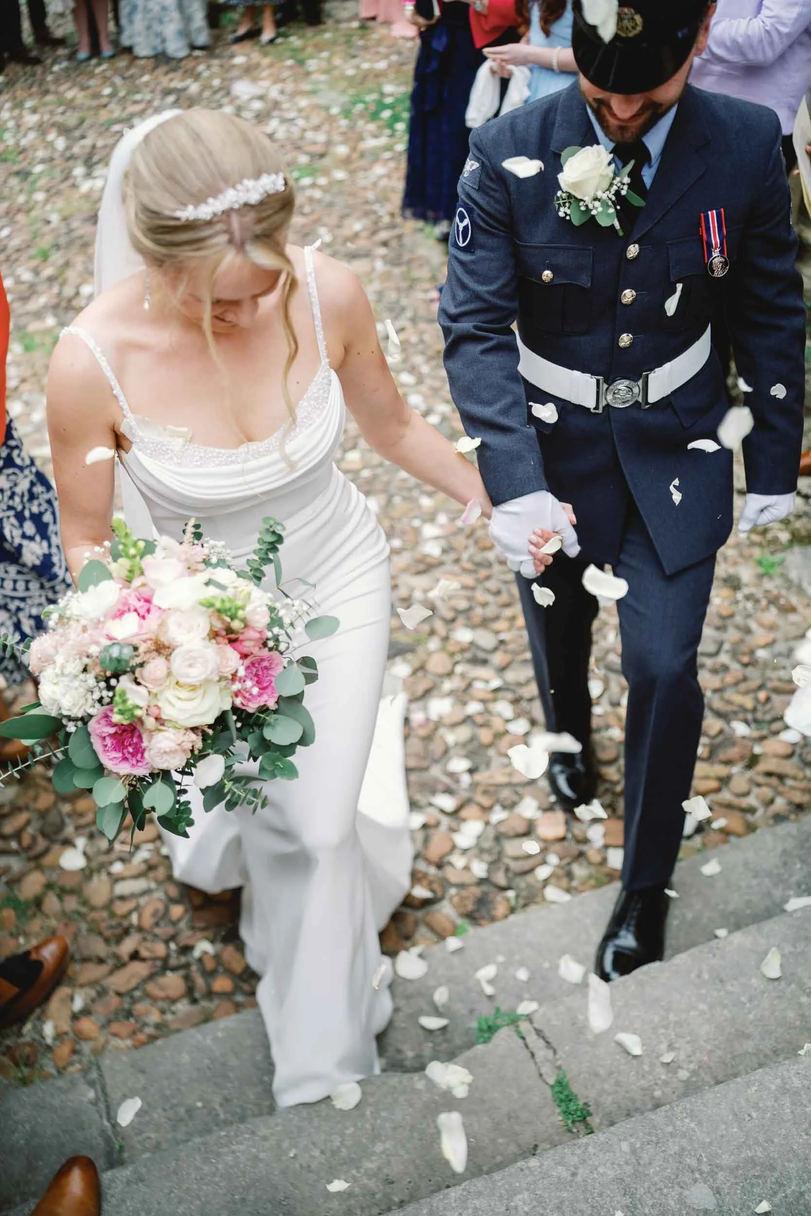 Bride and groom in military dress walking through confetti at Saint-Jacques Church, Aubeterre-sur-Dronne