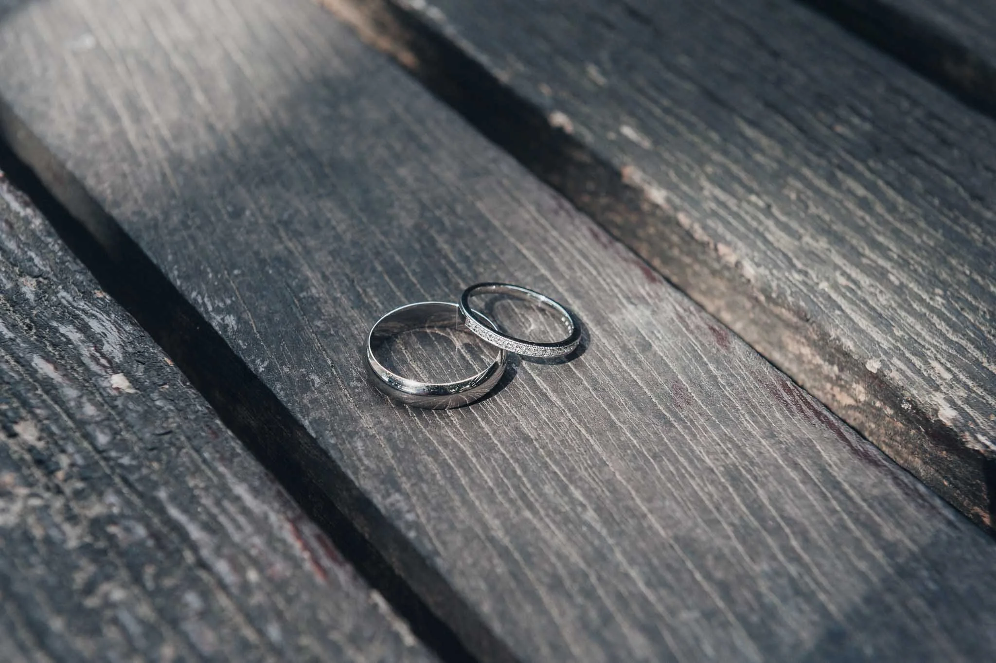 Wedding rings placed on a wooden surface, photographed as part of the morning details.