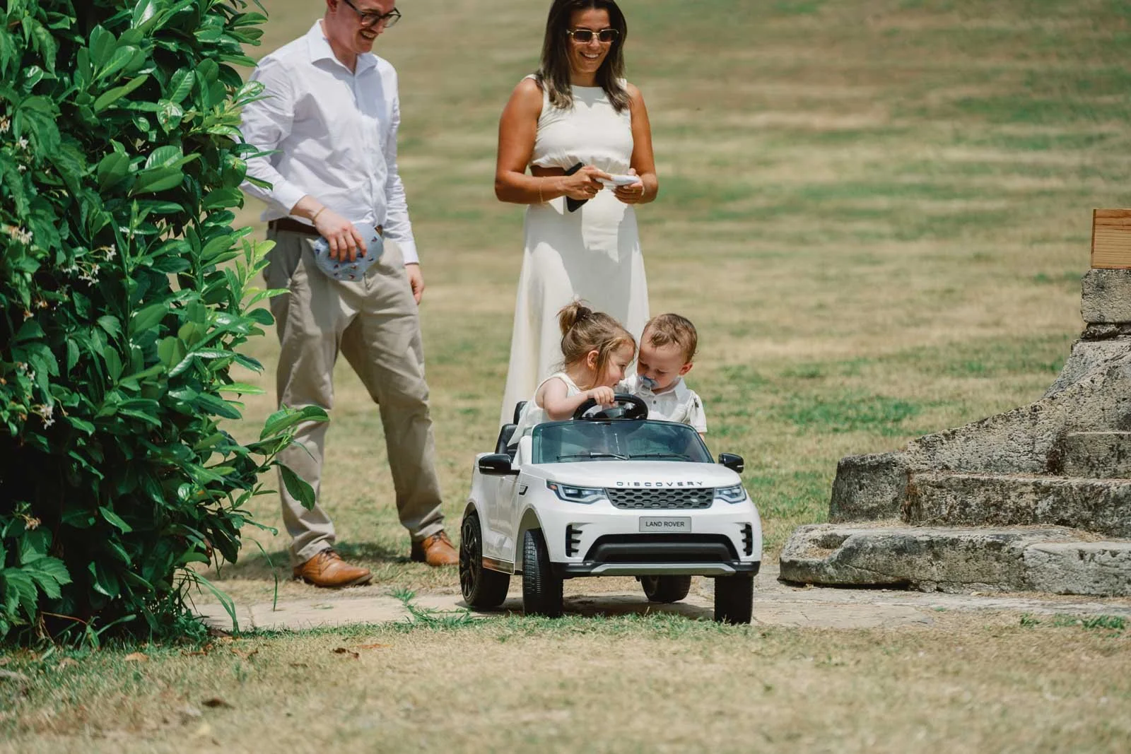 Two young children arriving down the aisle in a white remote control car at Château Lagorce