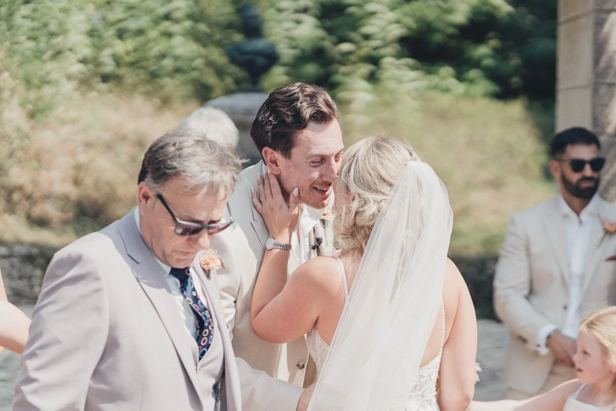 Bride meeting the groom at the altar and sharing a kiss during the outdoor ceremony.