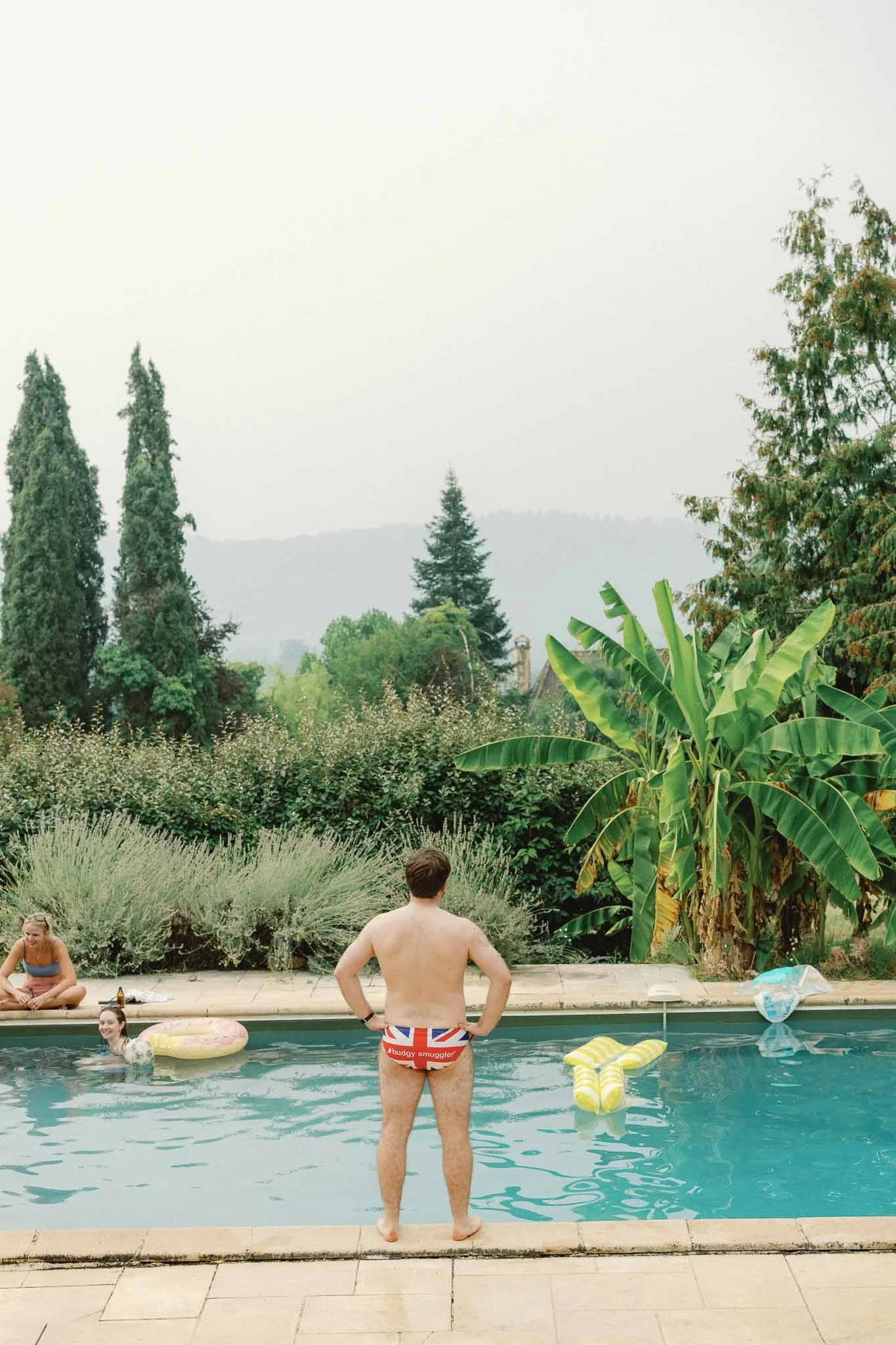 A wedding guest standing at the pool edge at Château du Raysse, Dordogne