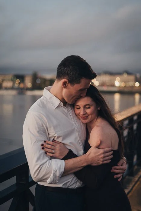Couple embracing quietly by the water during an evening engagement shoot in Bordeaux.