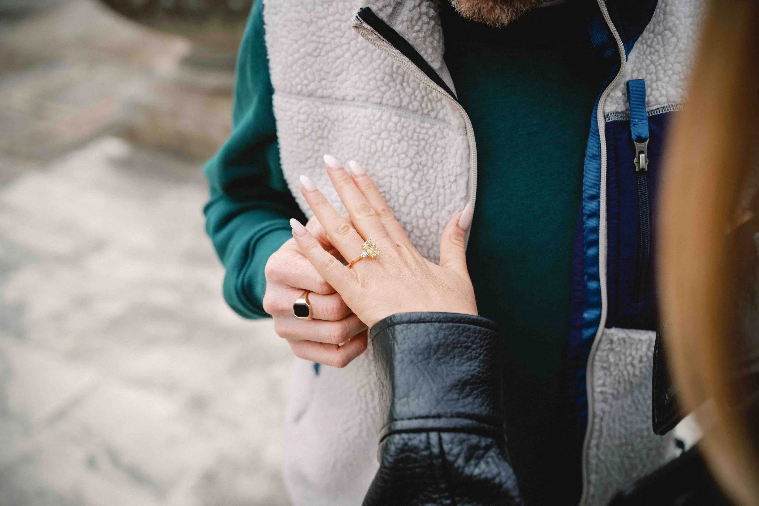 Close-up of a new engagement ring with a yellow centre stone as she rests her hand on his chest after the proposal in Bordeaux