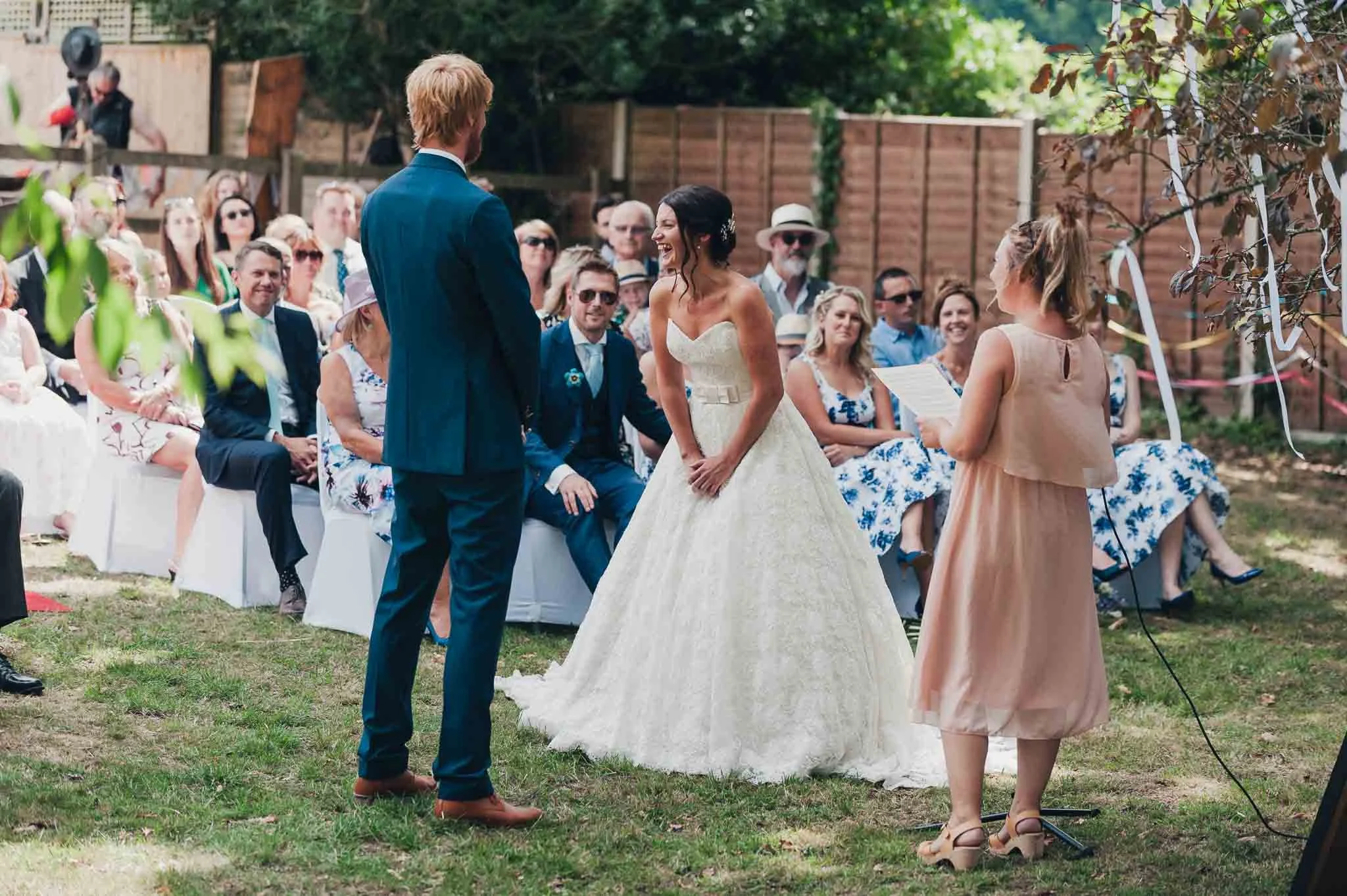 The bride and groom standing at the front of the outdoor ceremony surrounded by seated guests.