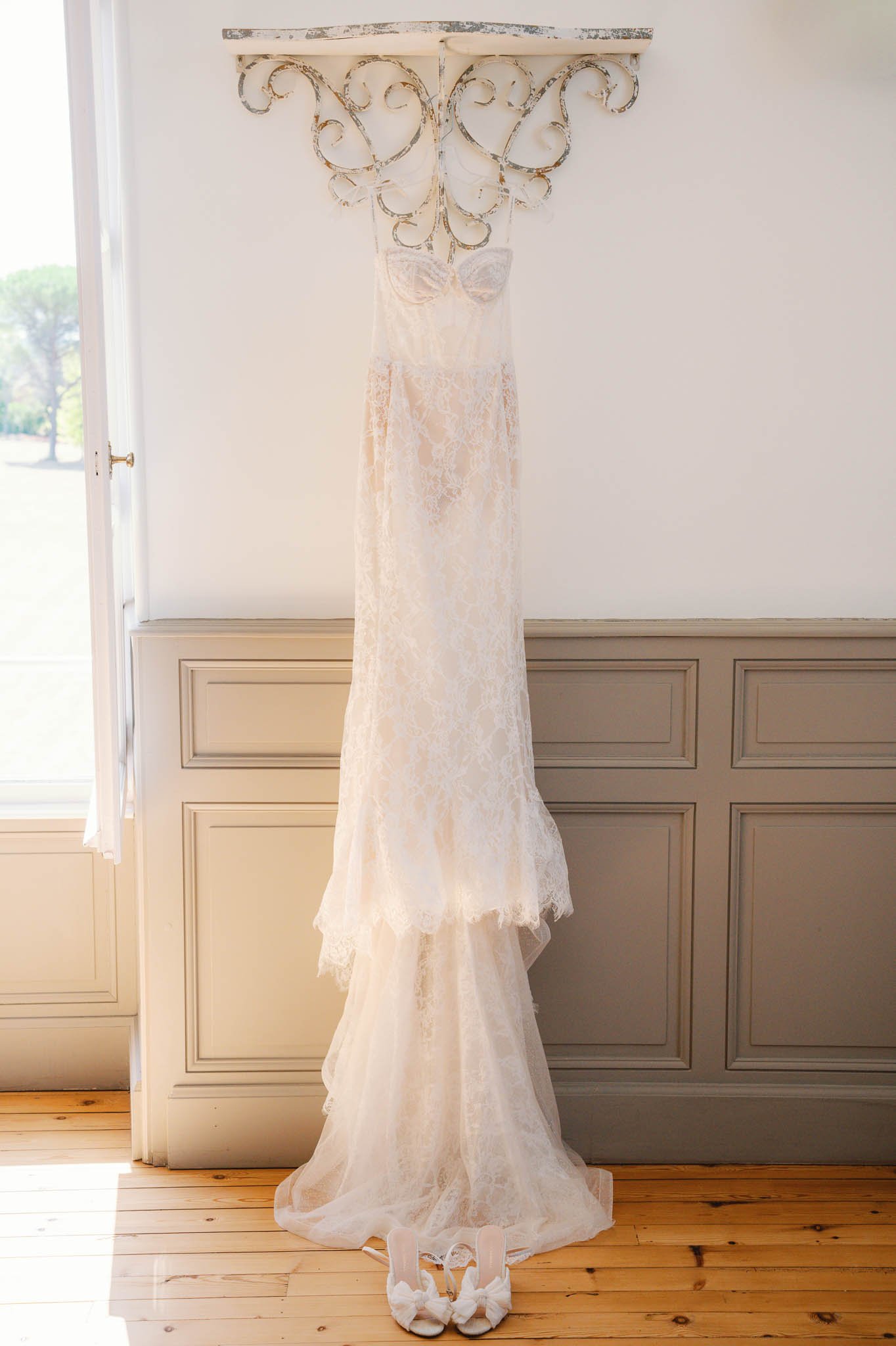 Wedding dress hanging in window light at Château de Sainte Croix, Dordogne