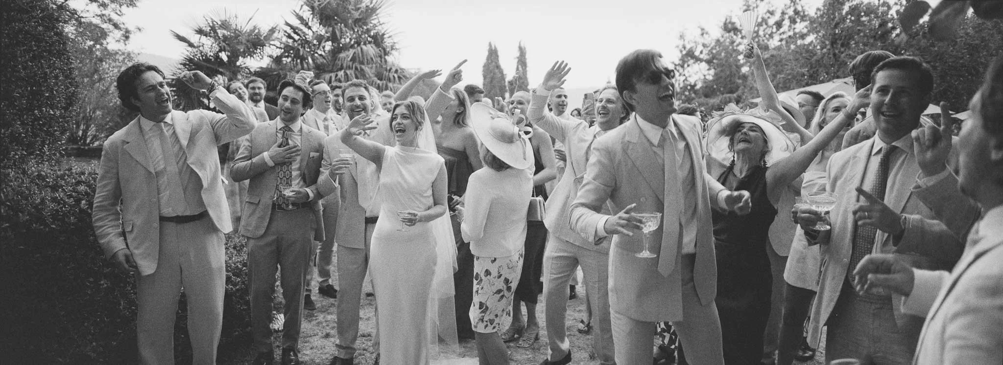 Panoramic film photograph of wedding guests singing at Château du Raysse, shot on Hasselblad XPan