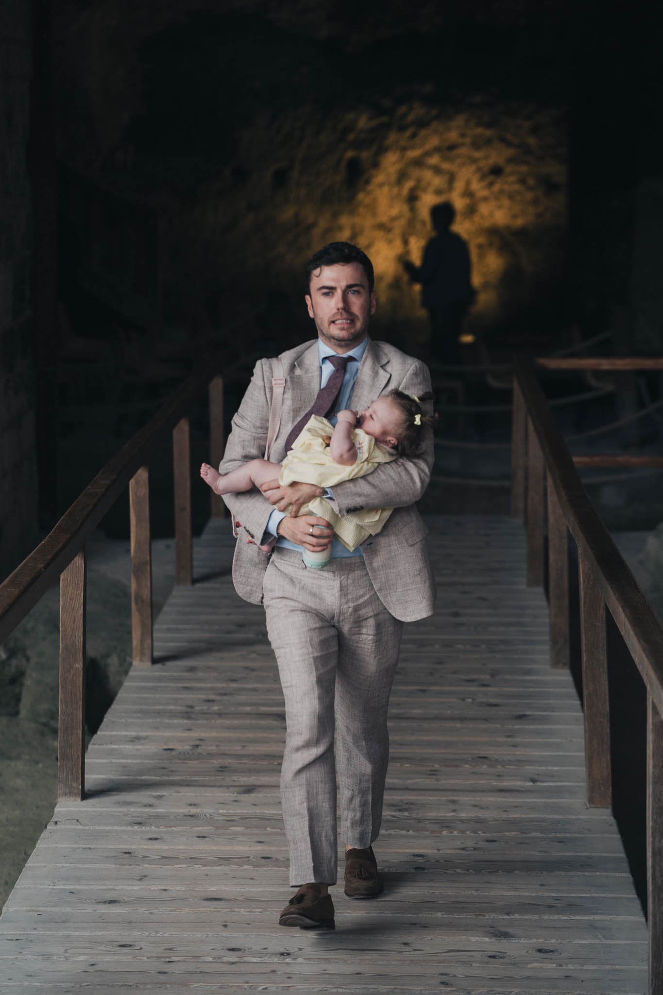 Guest carrying a baby while walking along the wooden walkway inside the Église Souterraine Saint-Jean.
