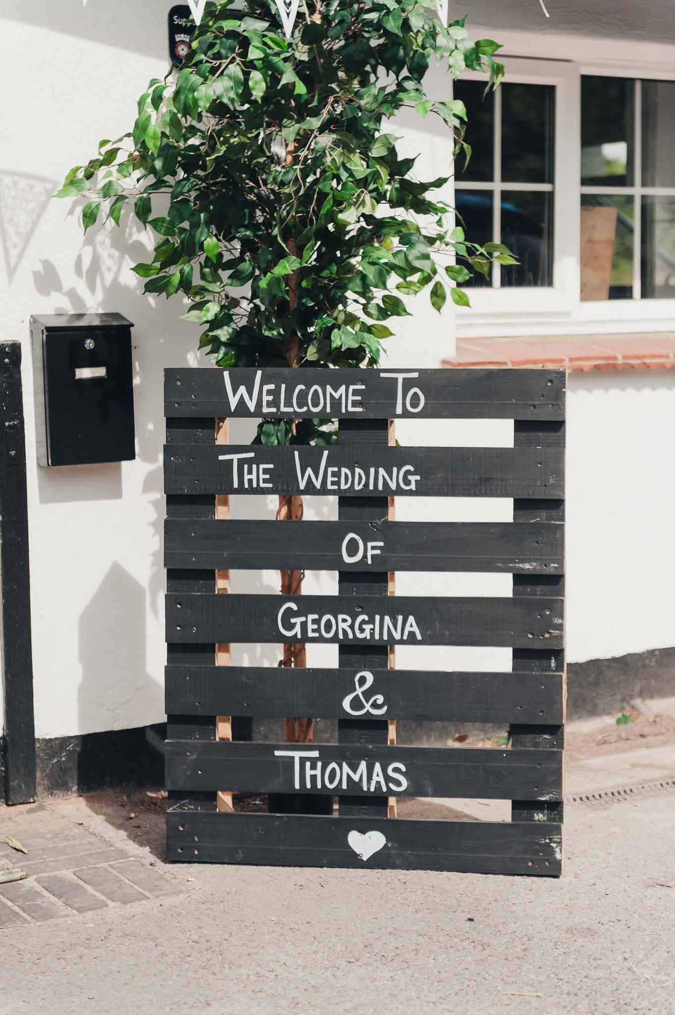 Hand-painted wooden wedding sign outside the venue welcoming guests.