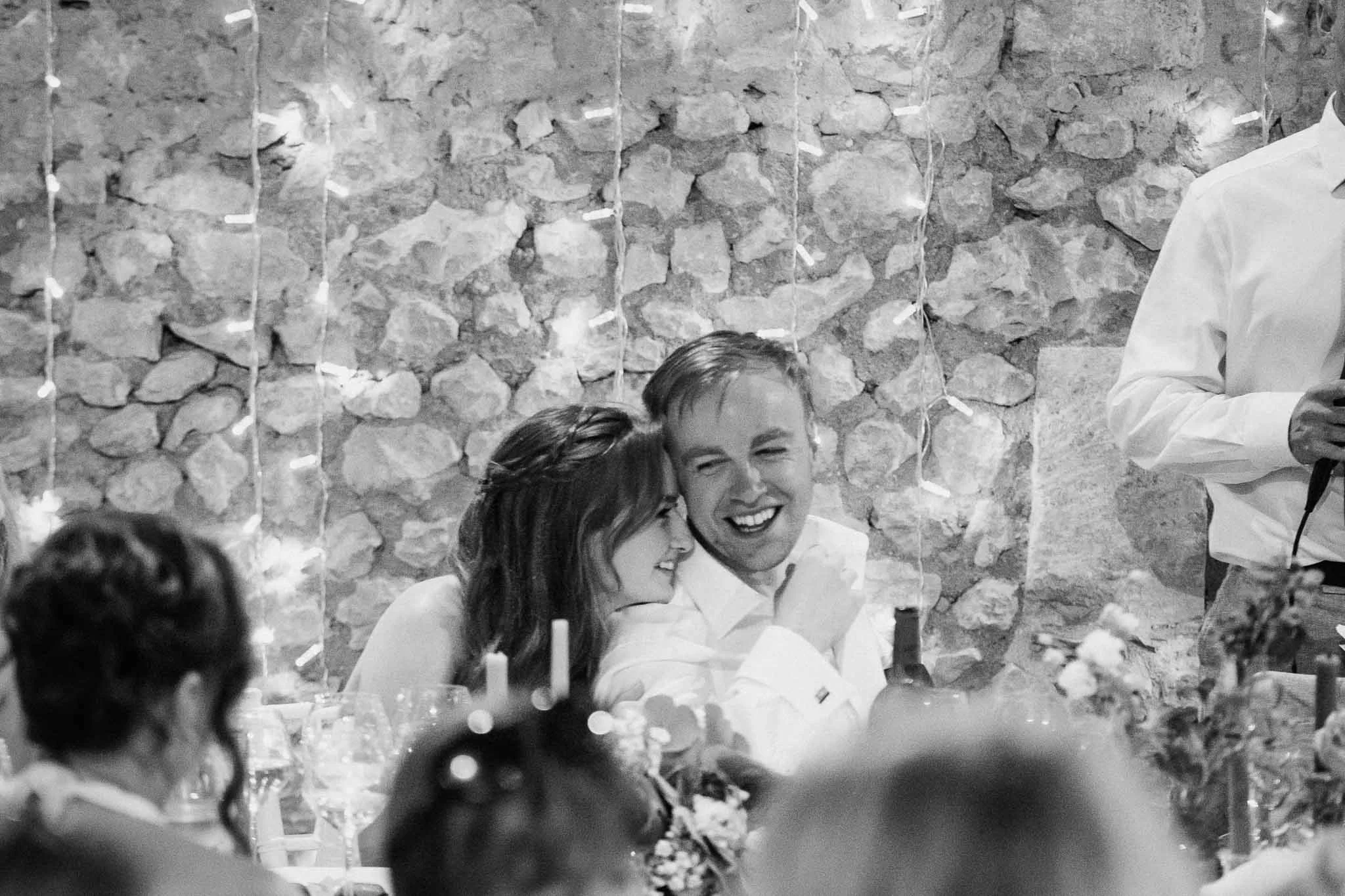 Bride and groom sharing a quiet moment, leaning into each other, during the speeches.