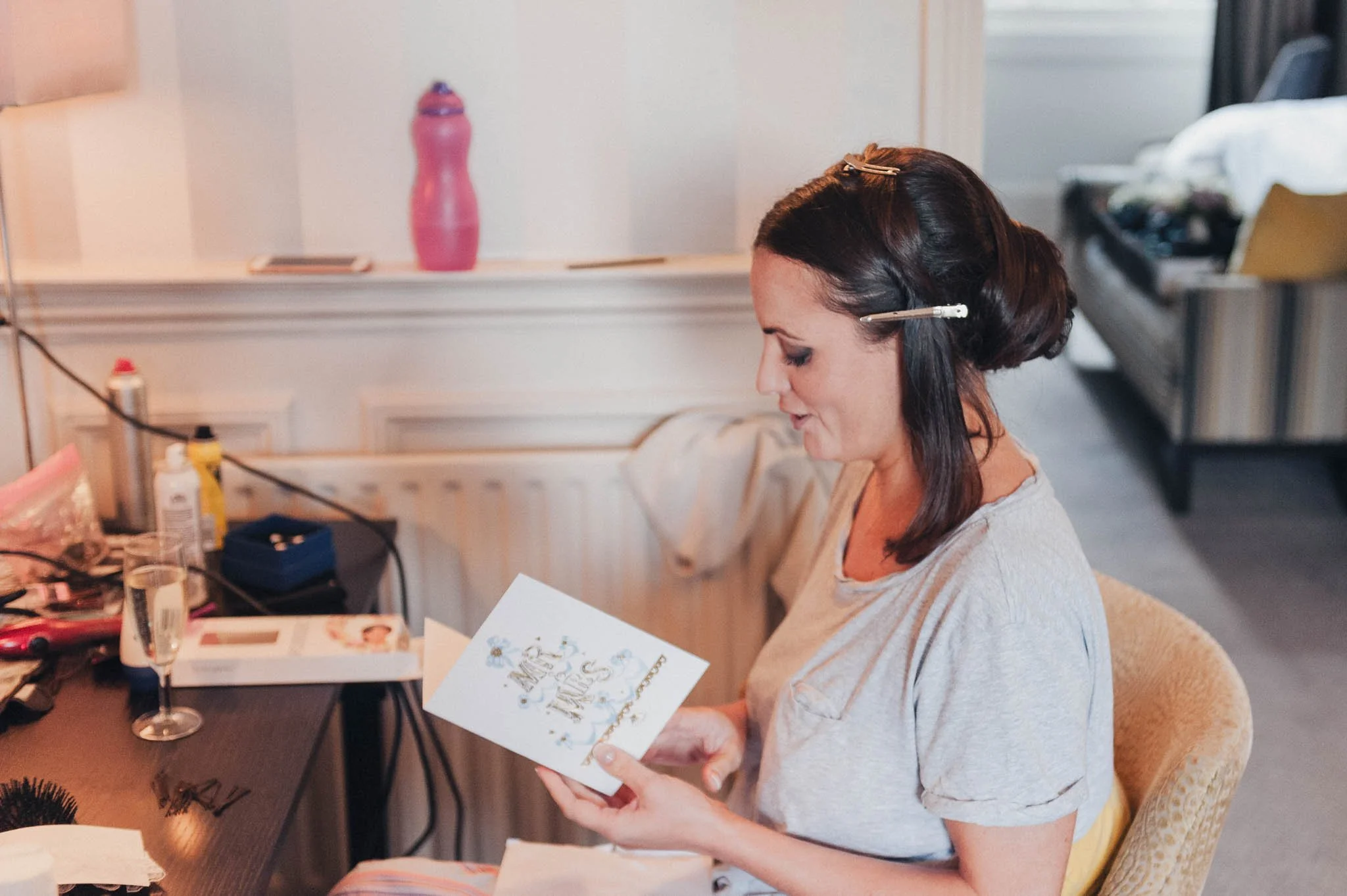 Bride reading a card during the morning preparations, sitting at a dressing table.