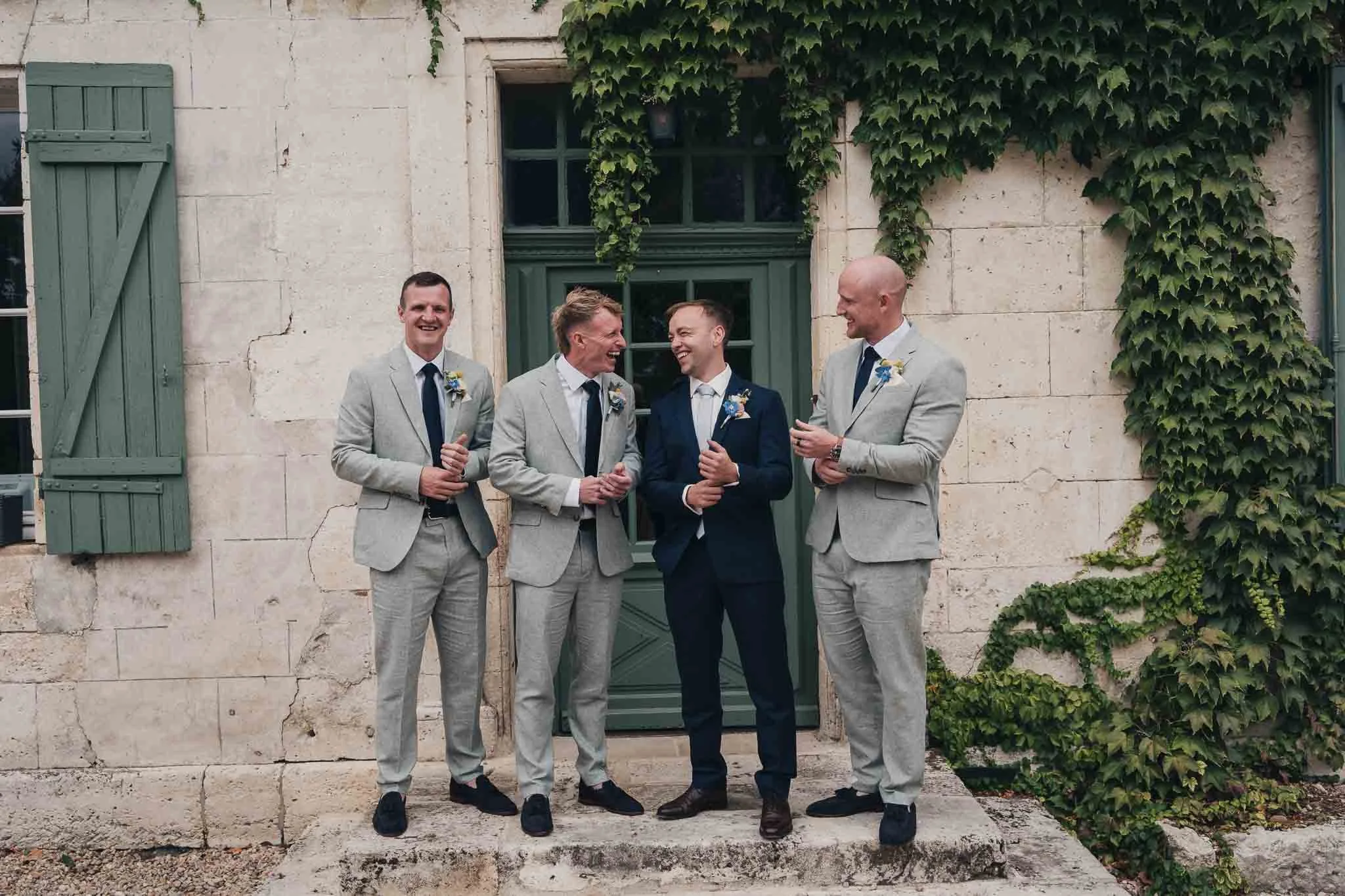Groom and groomsmen standing together outside Manoir de Longeveau before the ceremony.