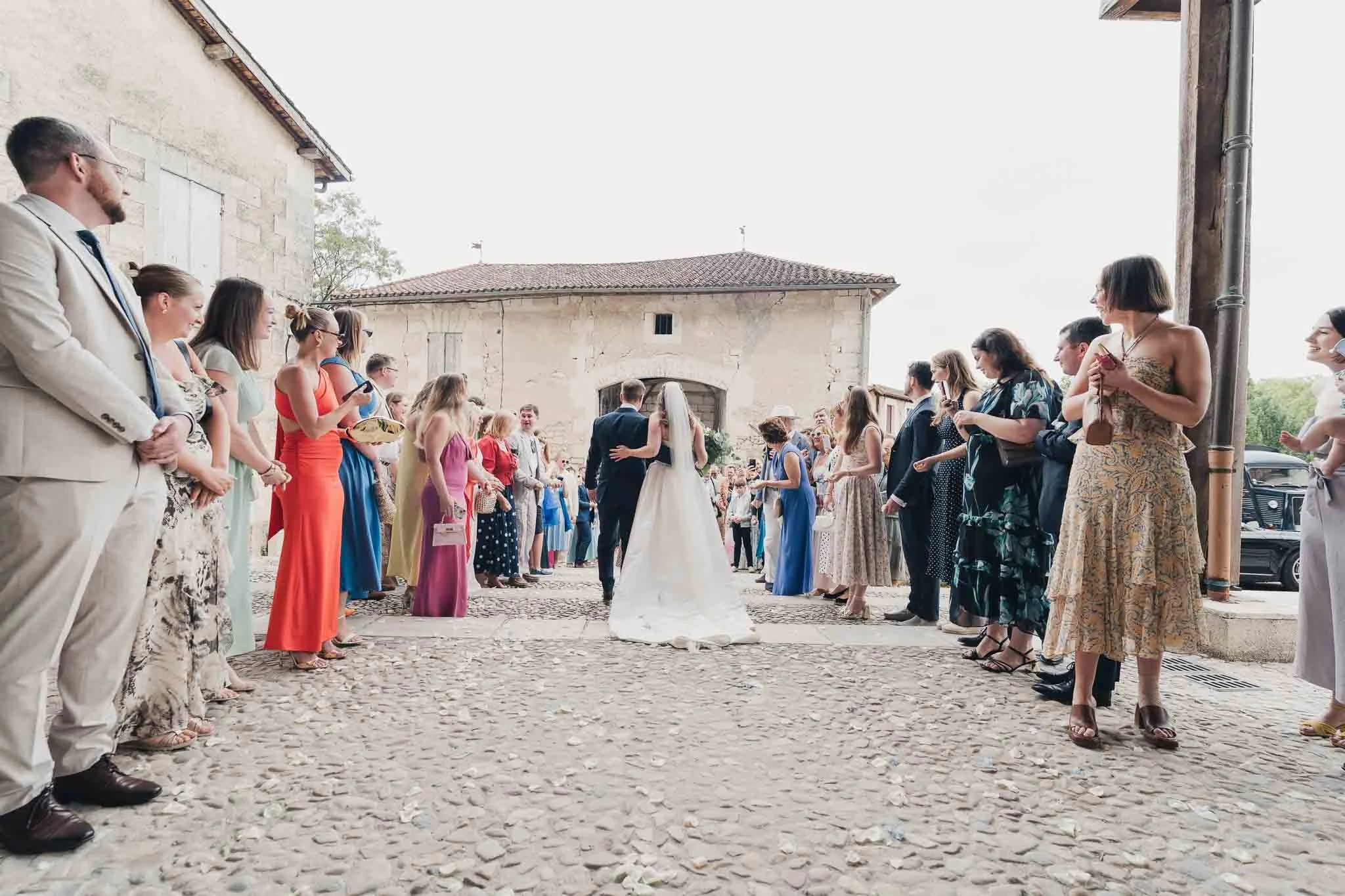 Bride and groom walking through two lines of guests for the confetti throw outside the church.