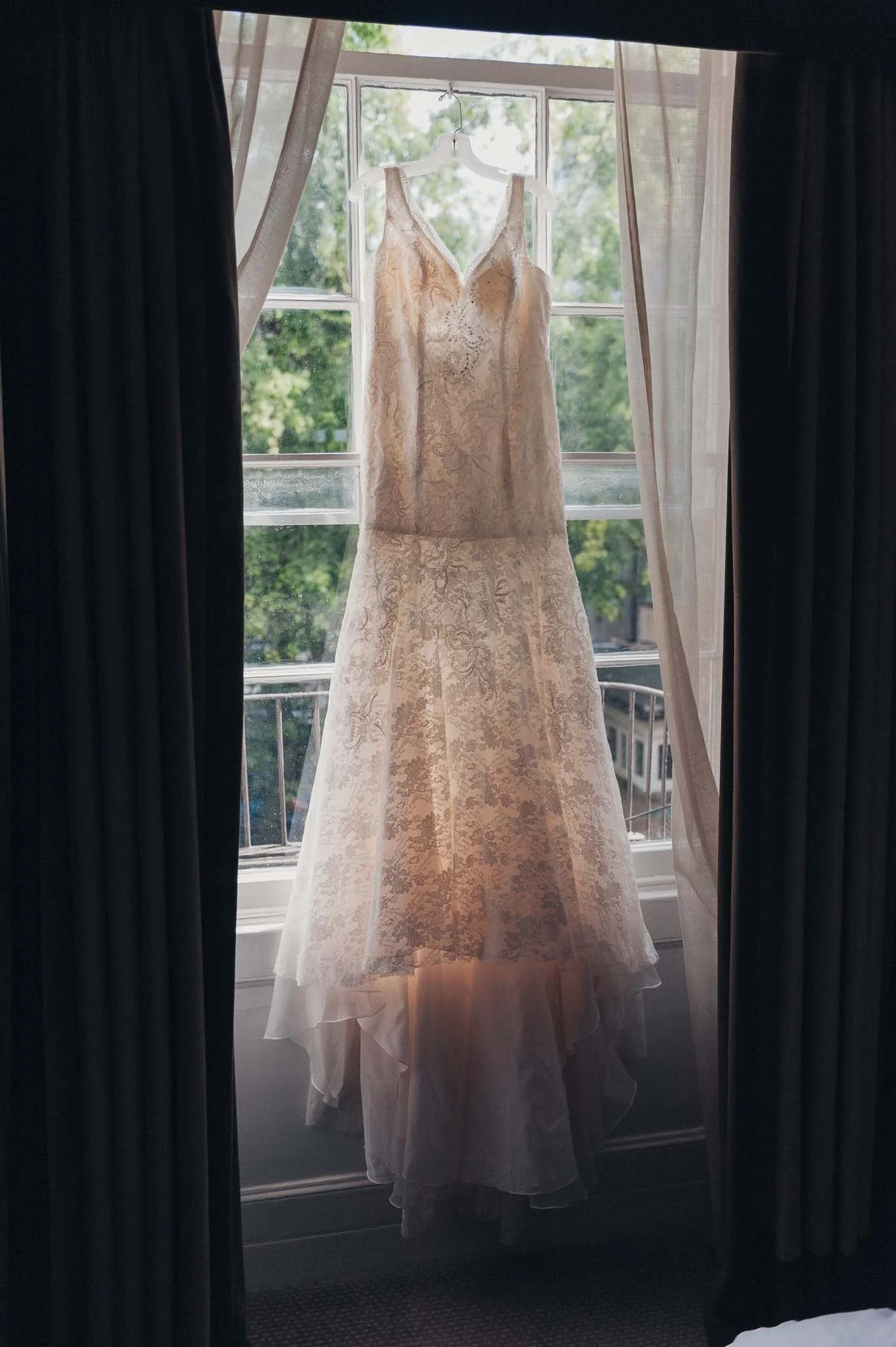 Bridal gown hanging in the window, photographed during the morning preparations.