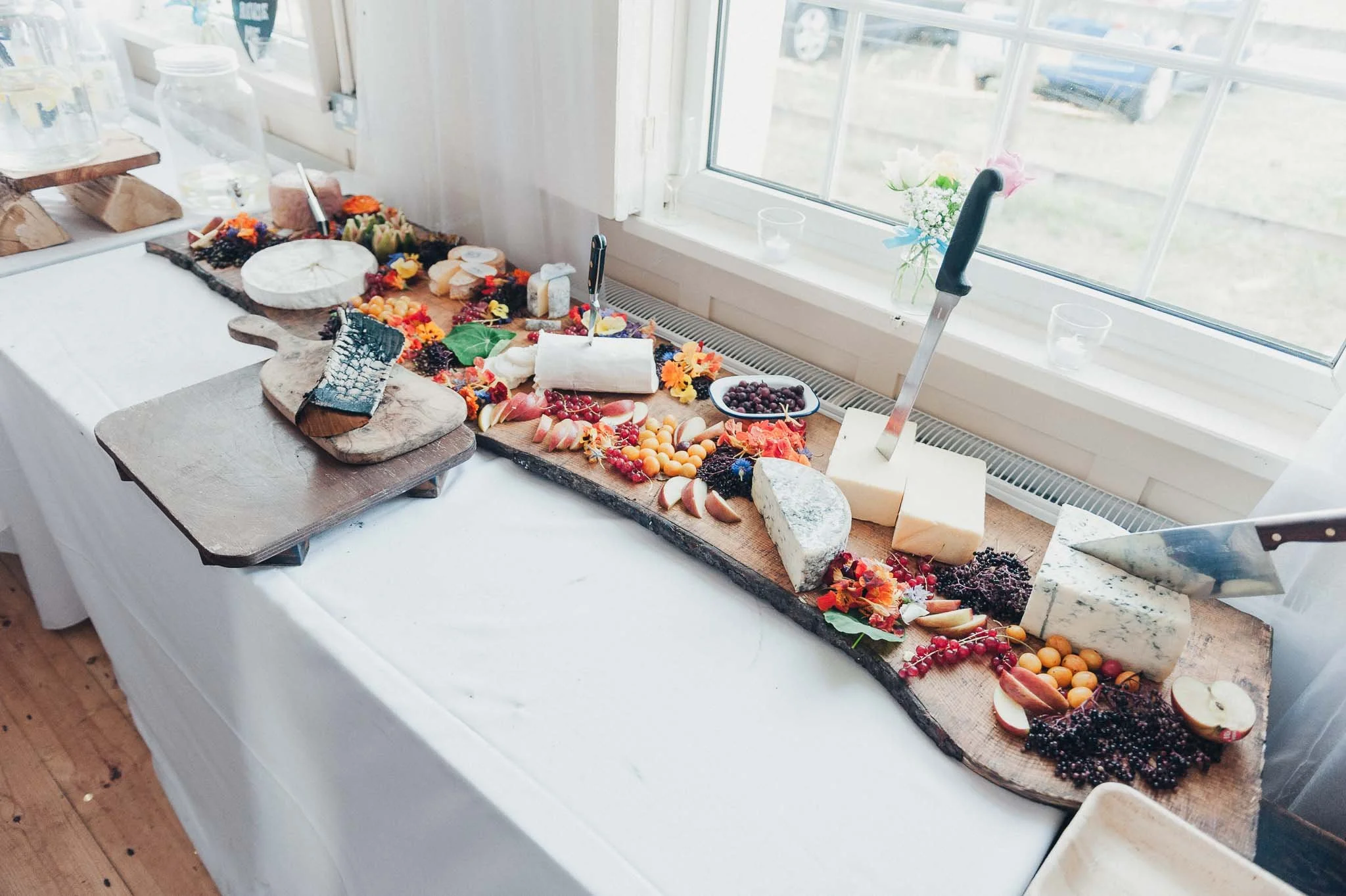 Long grazing table with cheeses, fruit, bread and charcuterie laid out for guests.