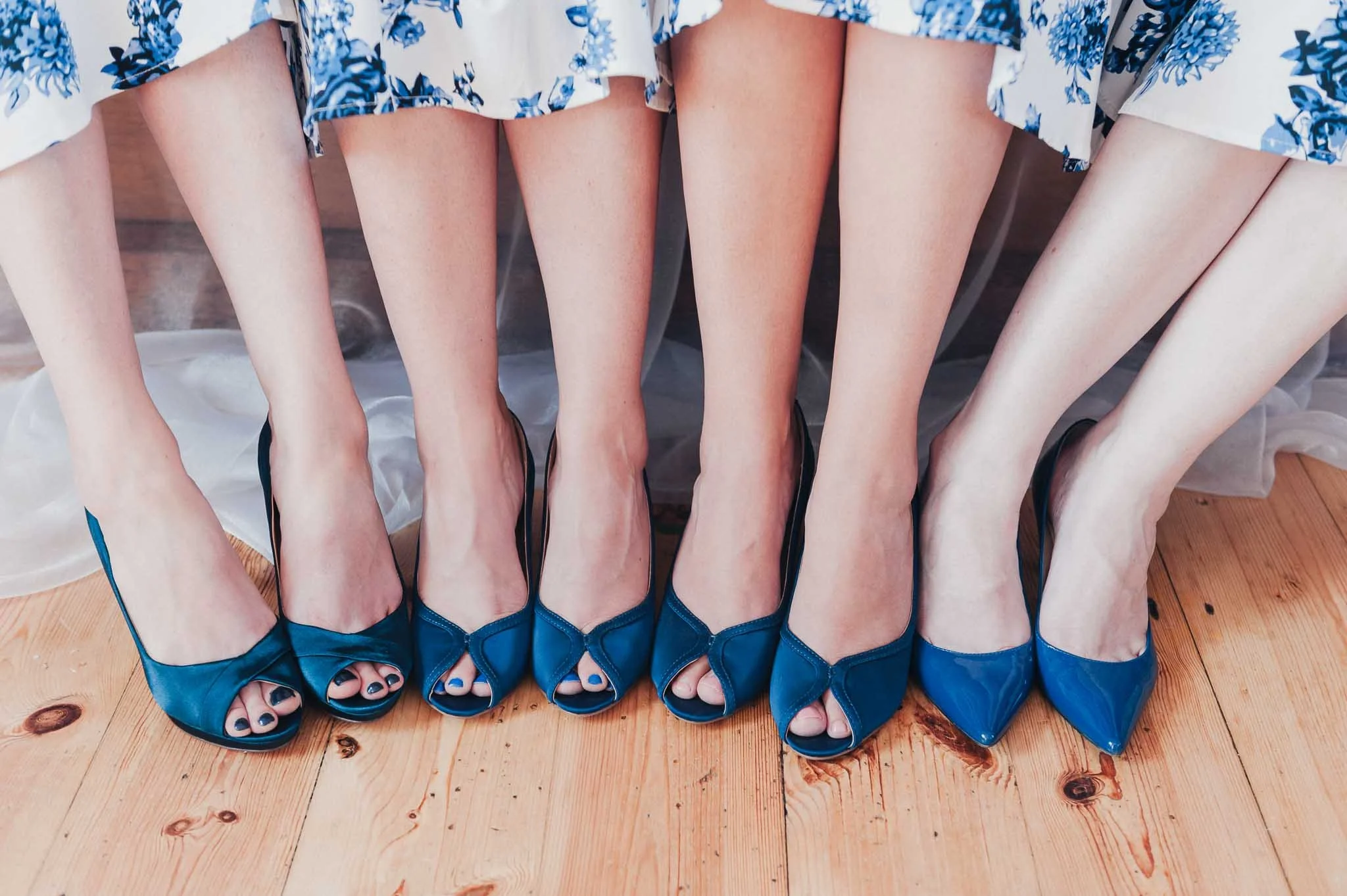 Bridesmaids sitting in a row showing their matching blue heels.