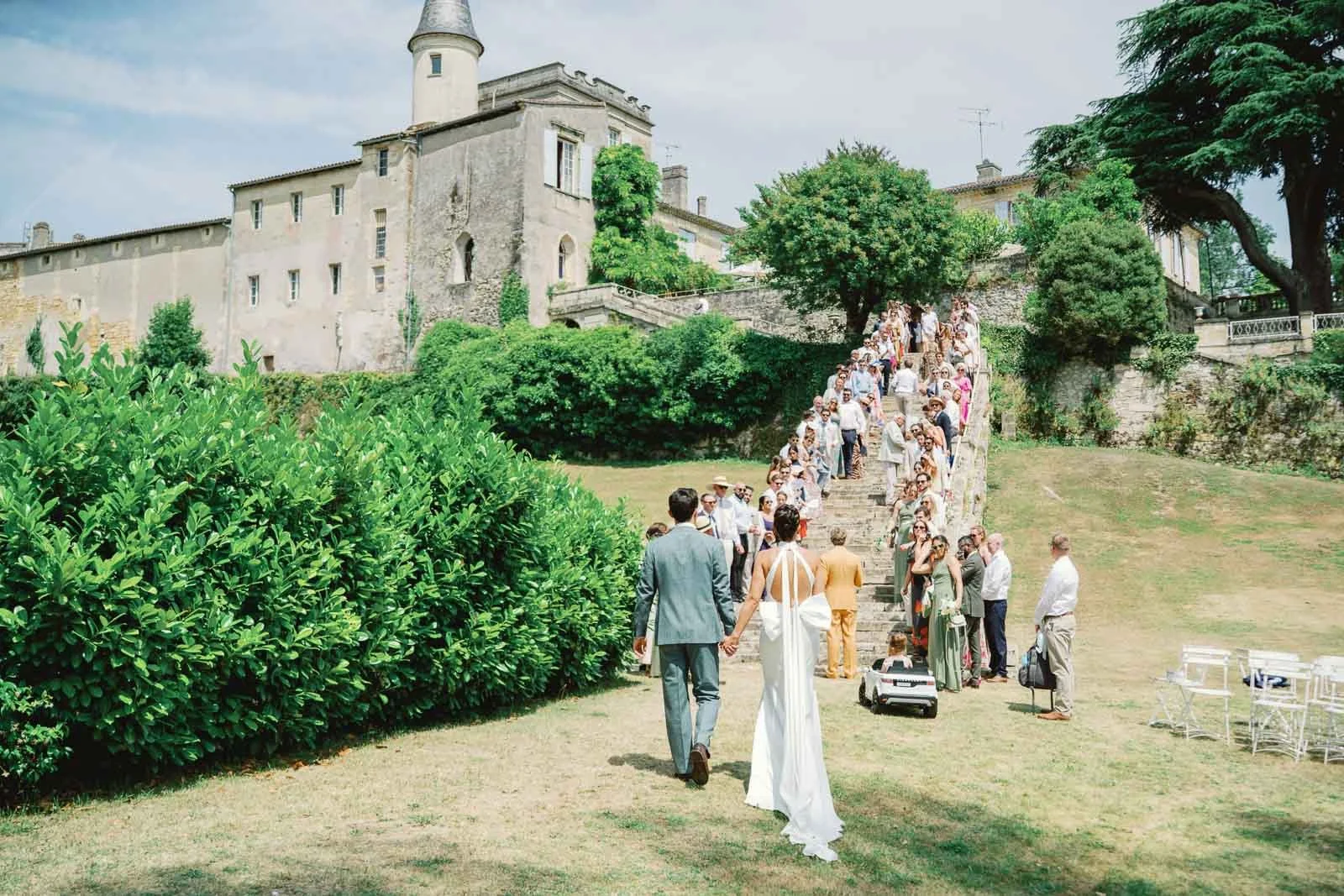 Wedding guests lining the stone staircase as the bride and groom walk up to Château Lagorce, Bordeaux